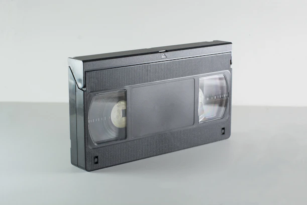 A black vhs video cassette tape on a grey surface.