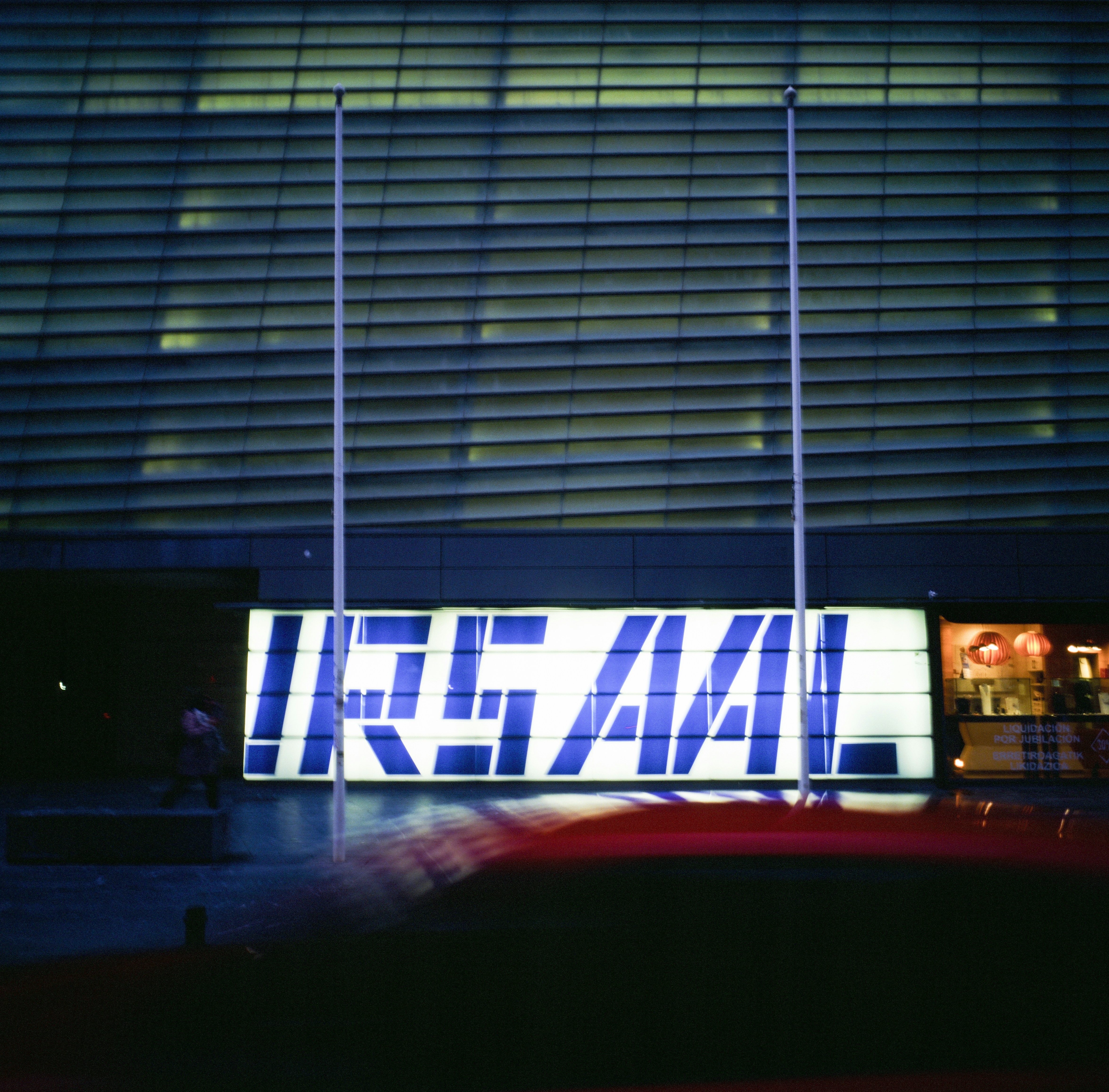 A glowing irsaal sign in front of a modern building