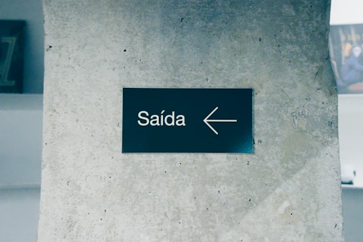 Saída sign with a left arrow on a concrete wall