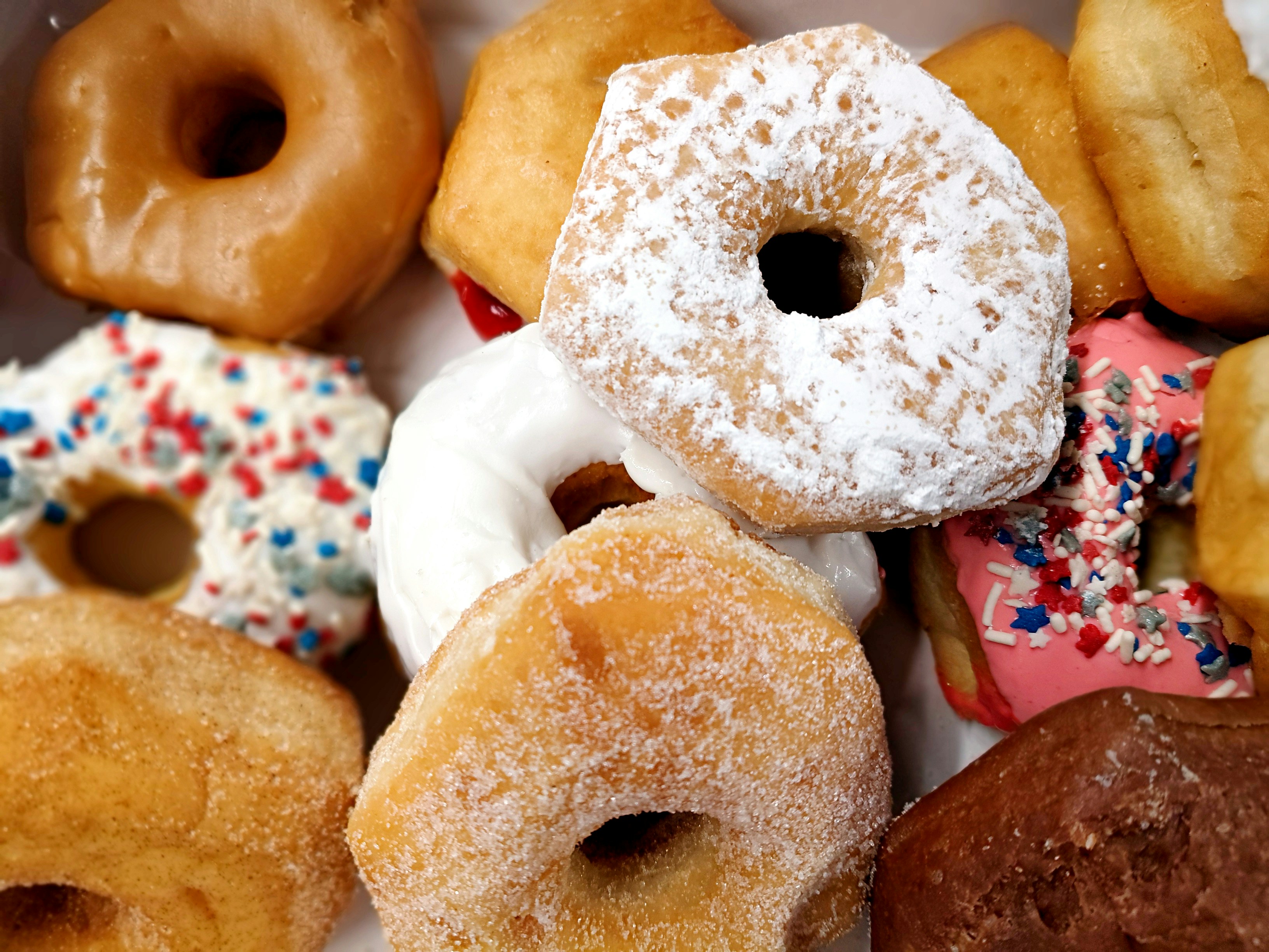 An appetizing selection of glazed, powdered, and sprinkled donuts
