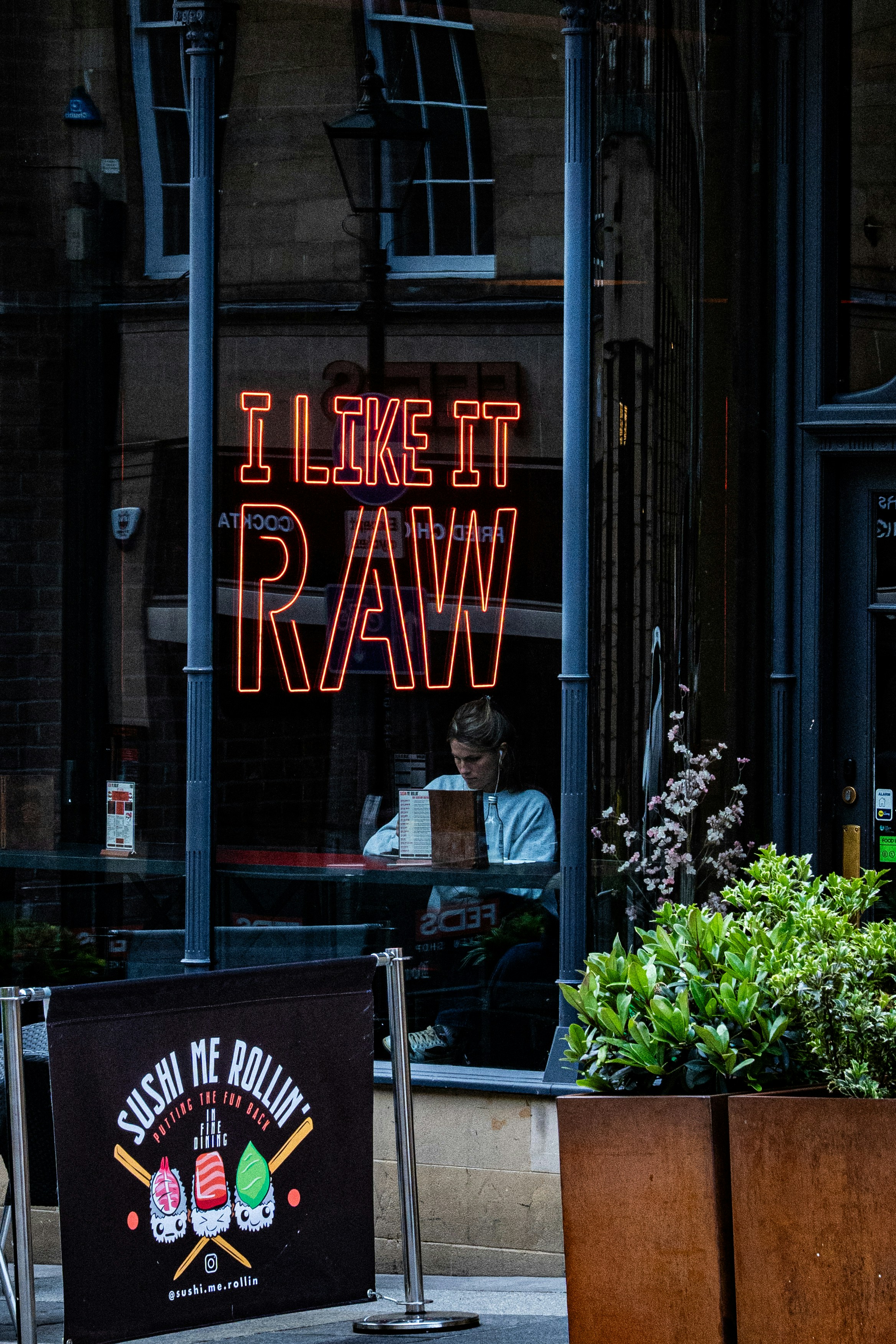 Neon sign "i like it raw" in a restaurant window.