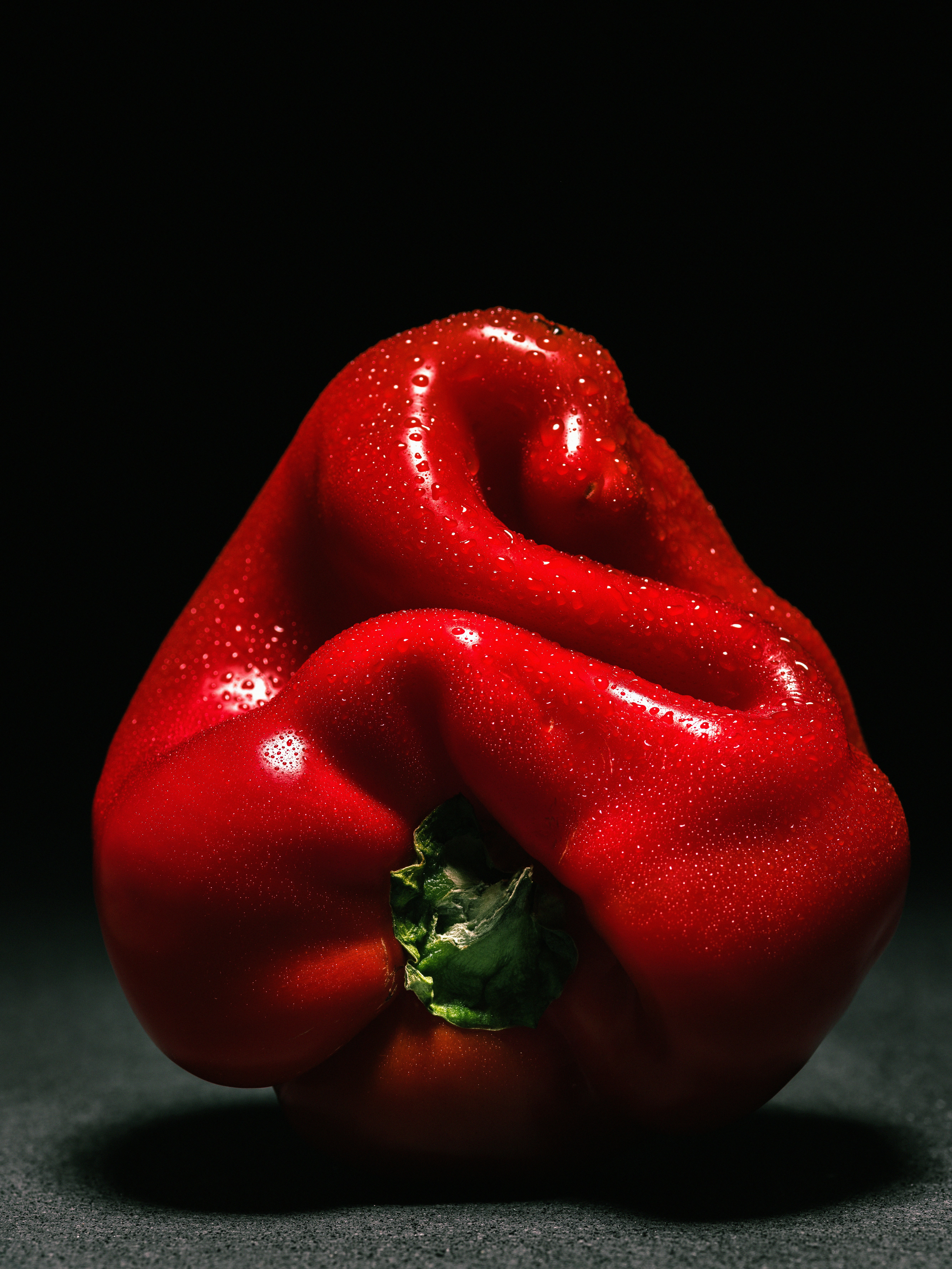 Vibrant red bell pepper covered in water droplets.