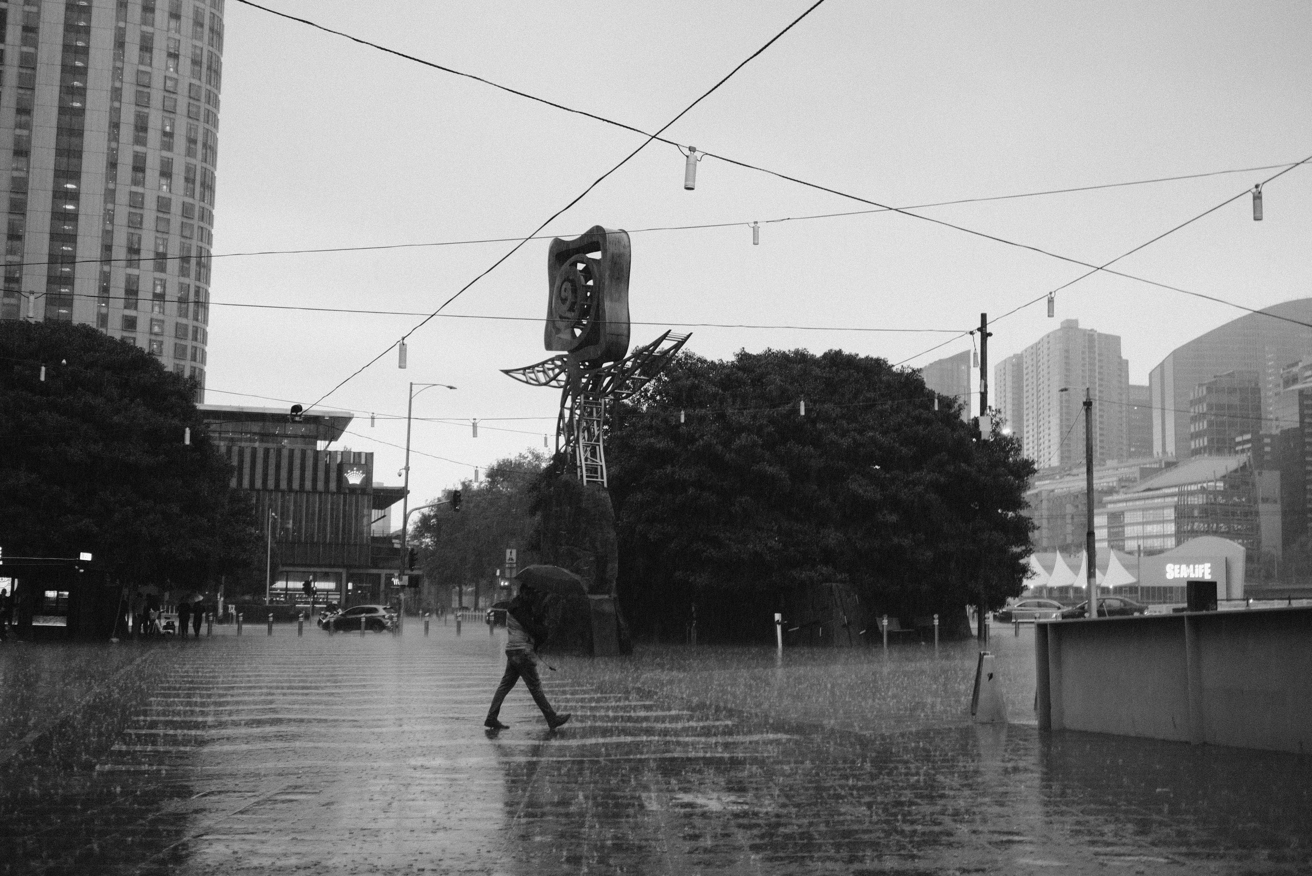 Solo person walks through a rain-flooded urban street.