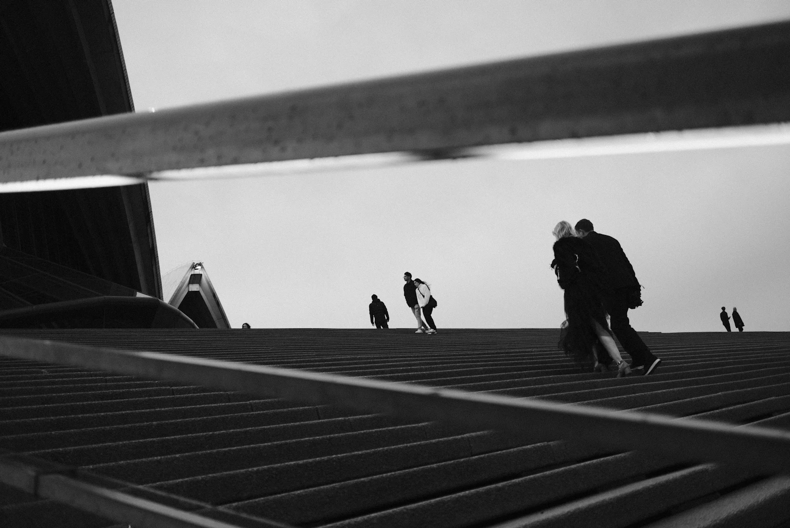 Silhouettes of people walking up a wide modern ramp in black and white