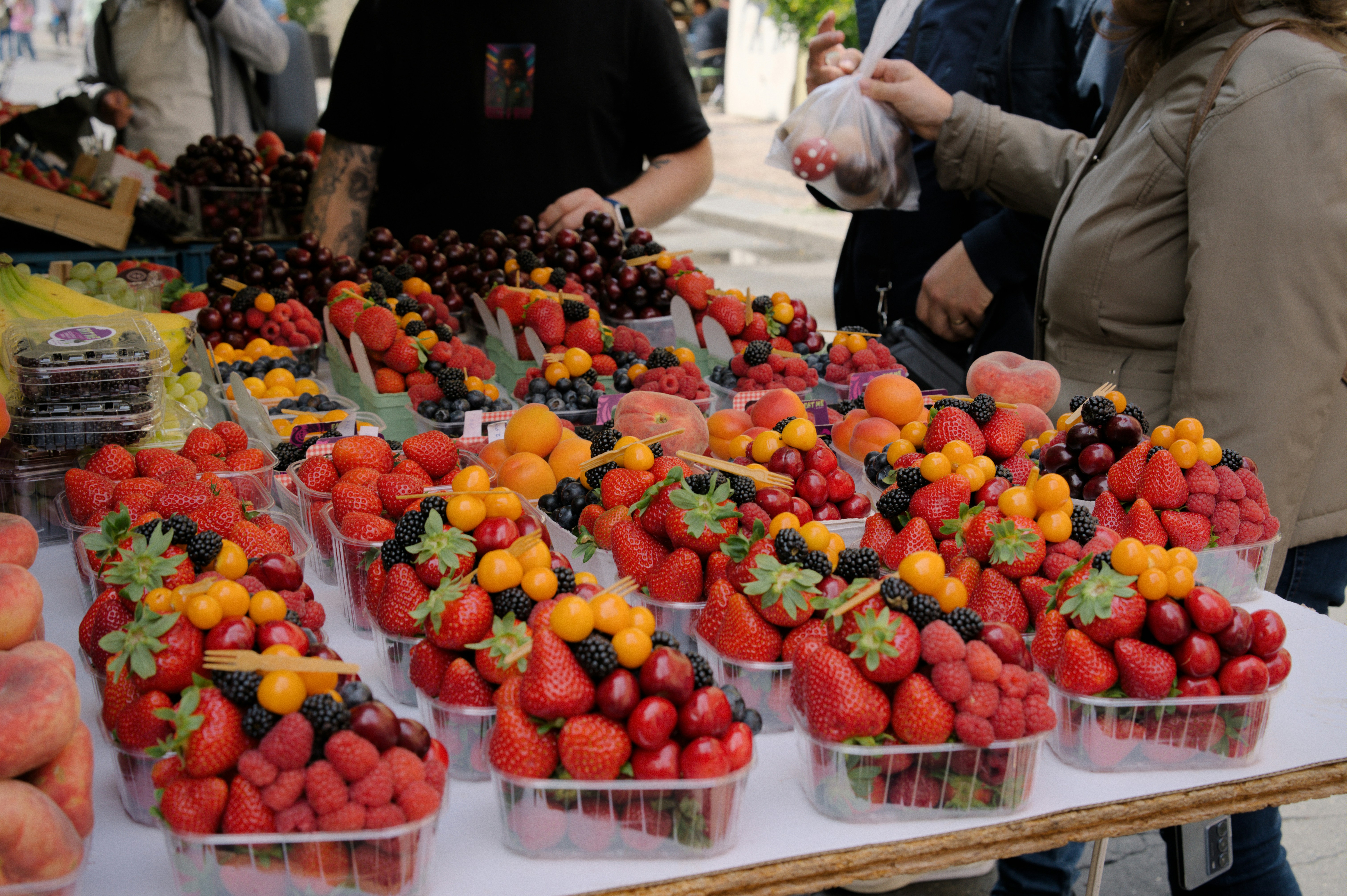 A market stall displays many fresh berries in plastic containers