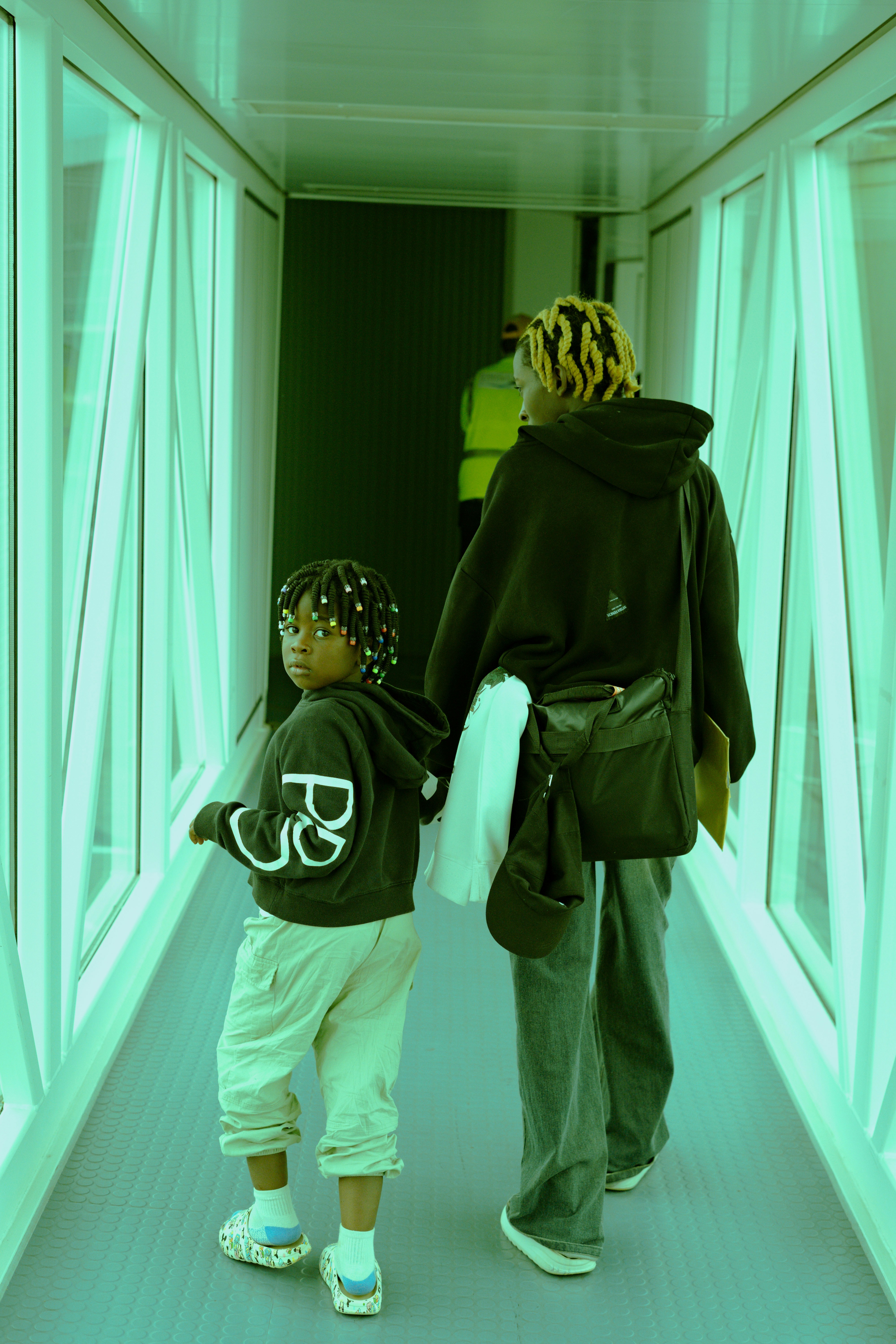 Adult and child walk through a green-lit jet bridge