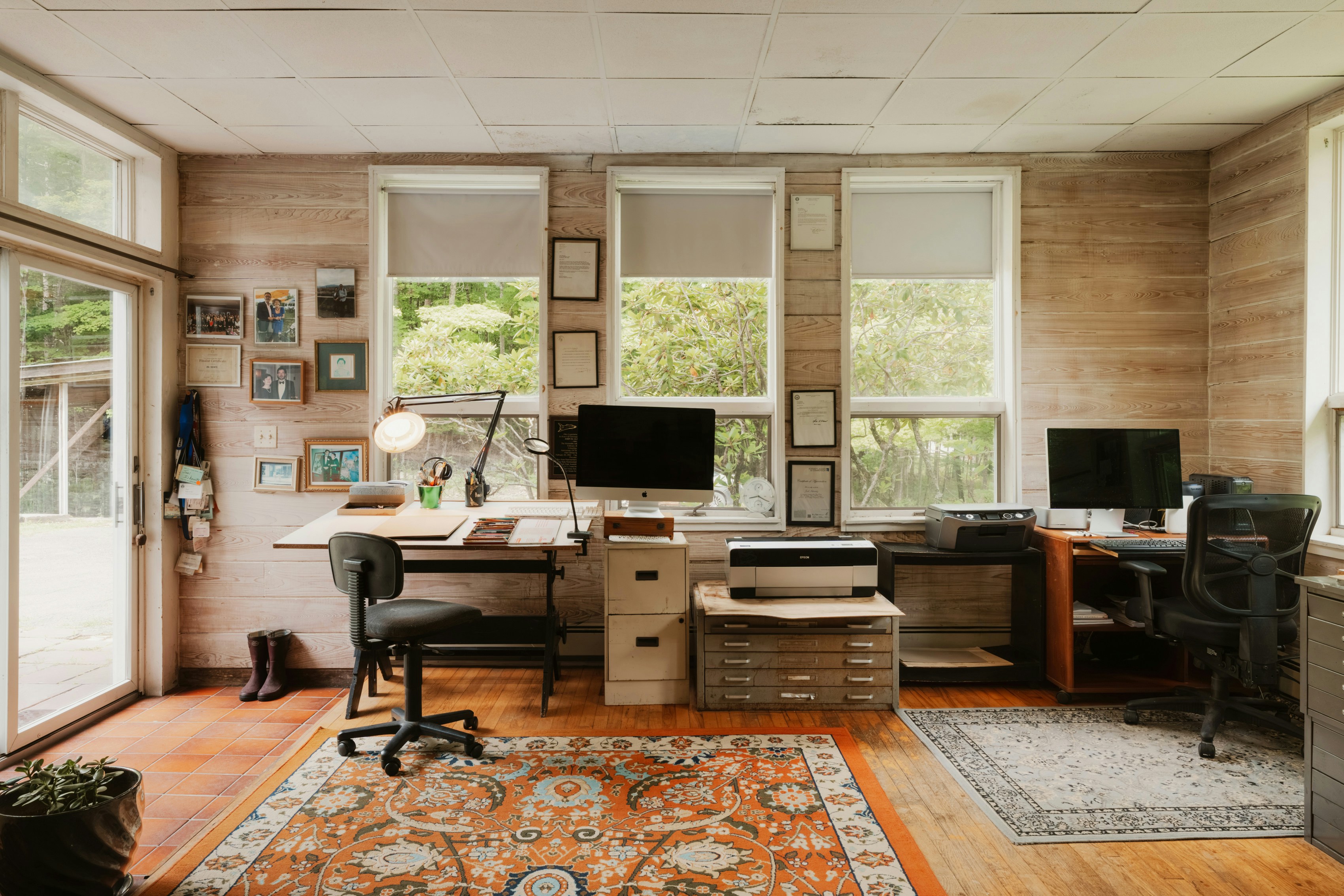 Home office with two desks, computers, and windows