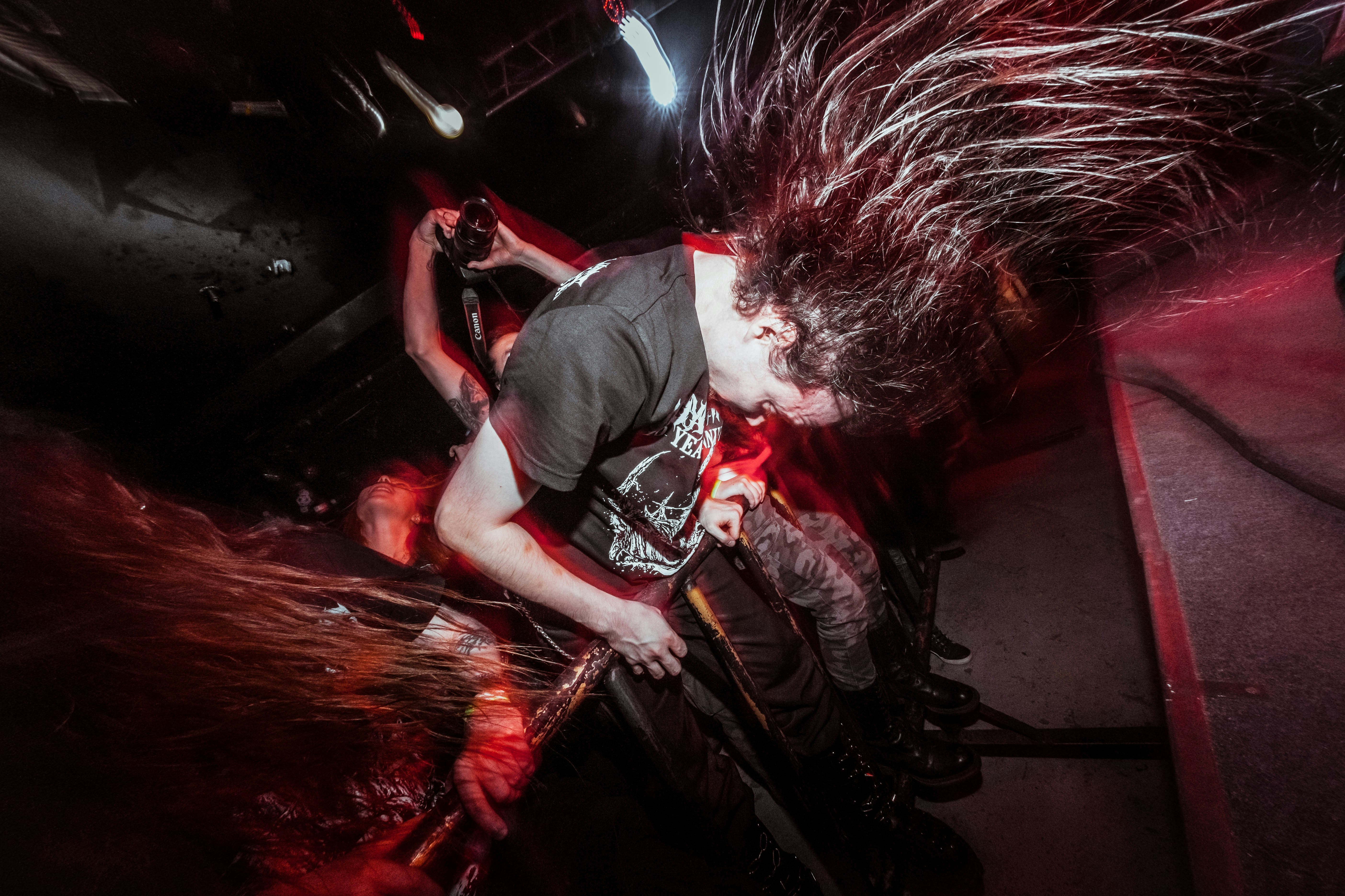 Energetic musician playing guitar with long hair flying.