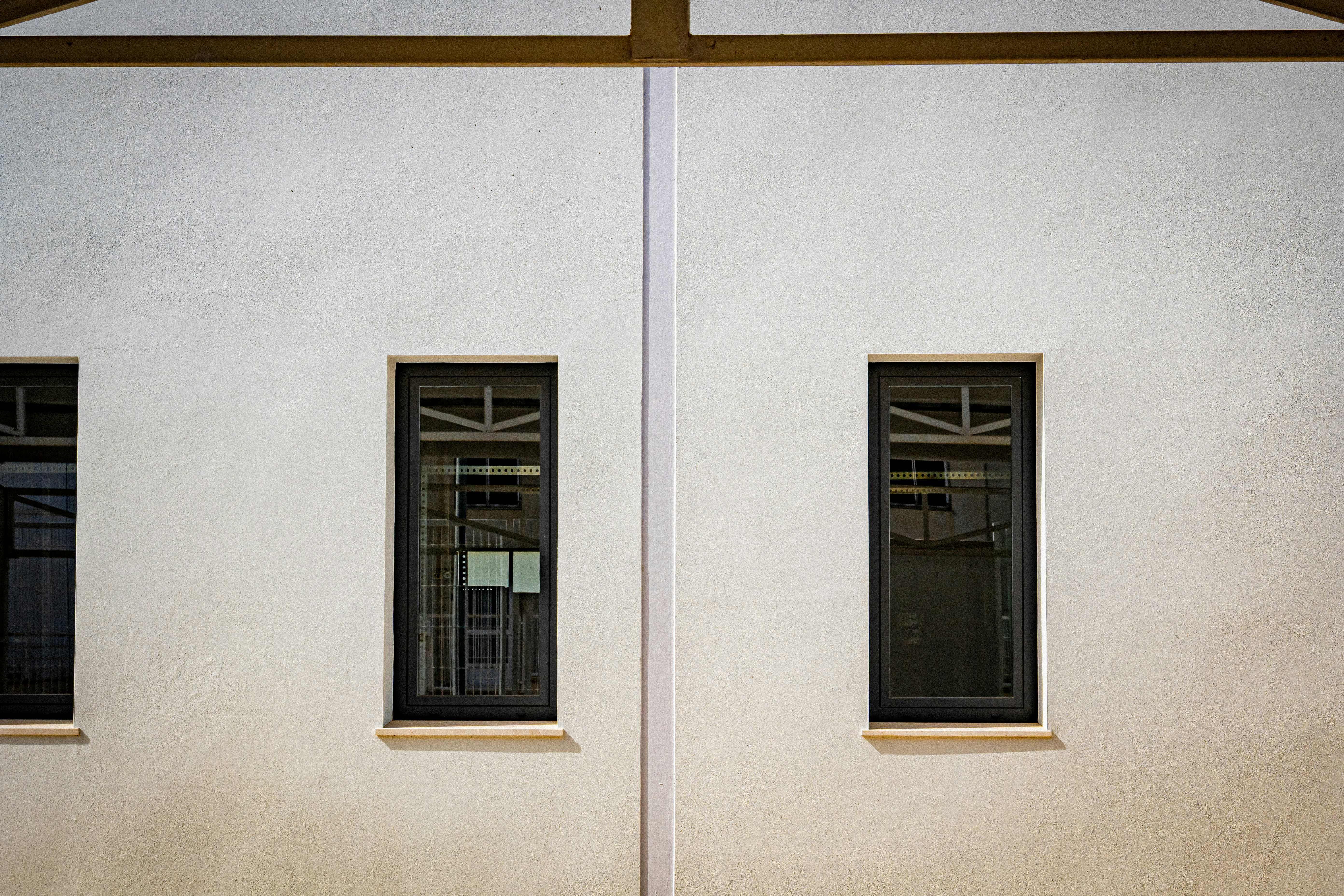 Modern white building exterior with symmetrical dark windows.