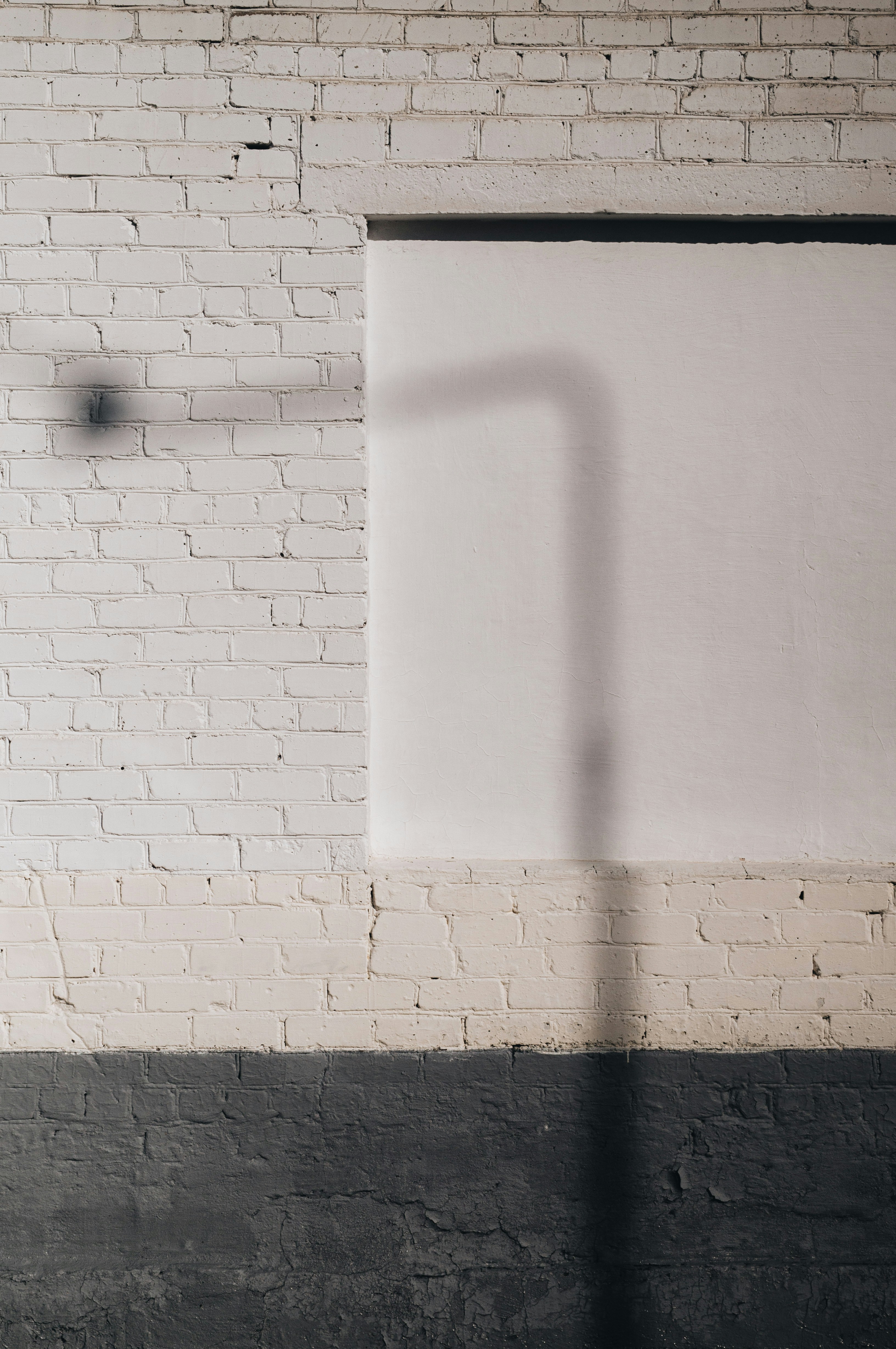 Street light shadow on a white brick and concrete wall.