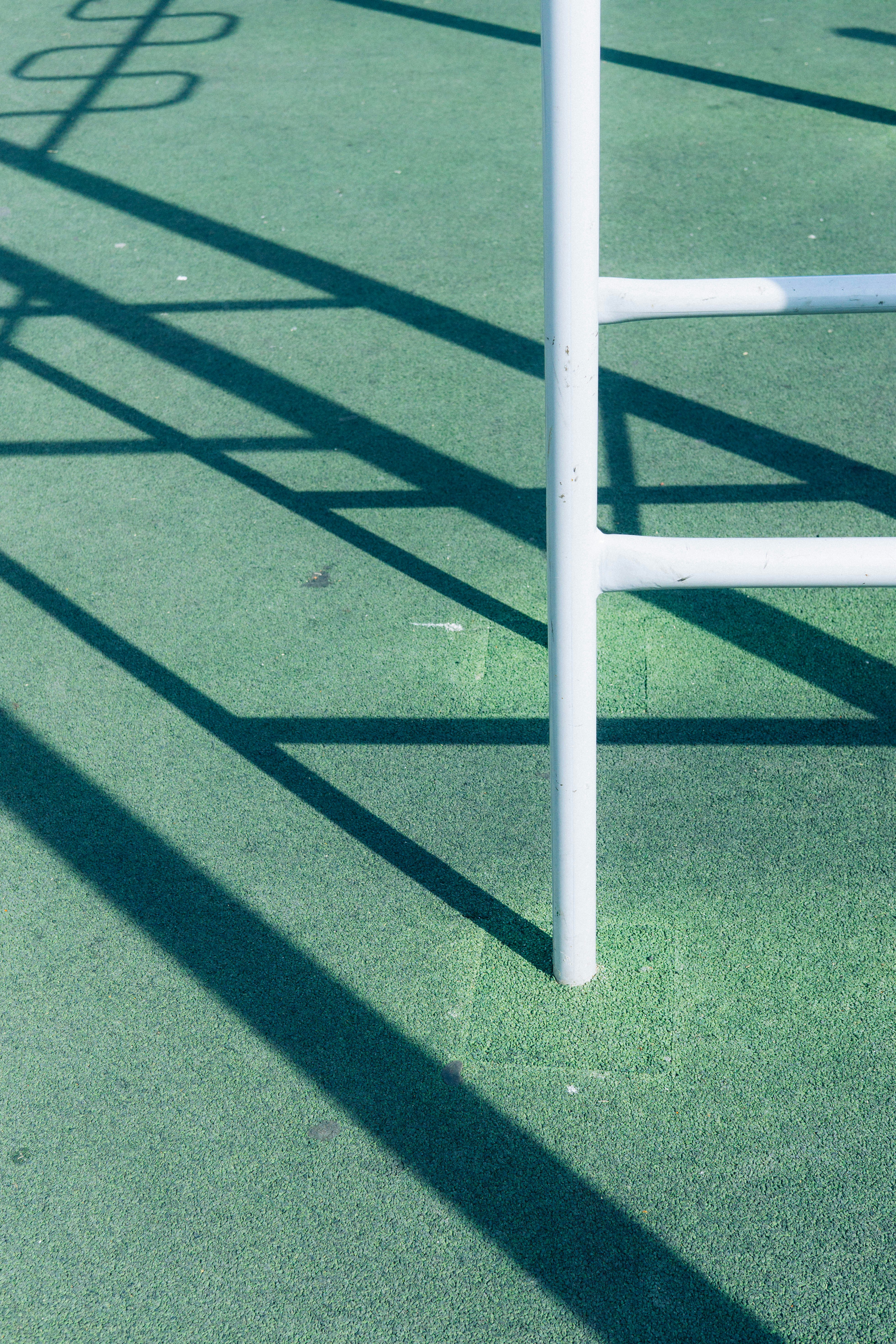 White metal structure casting long shadows on green surface.