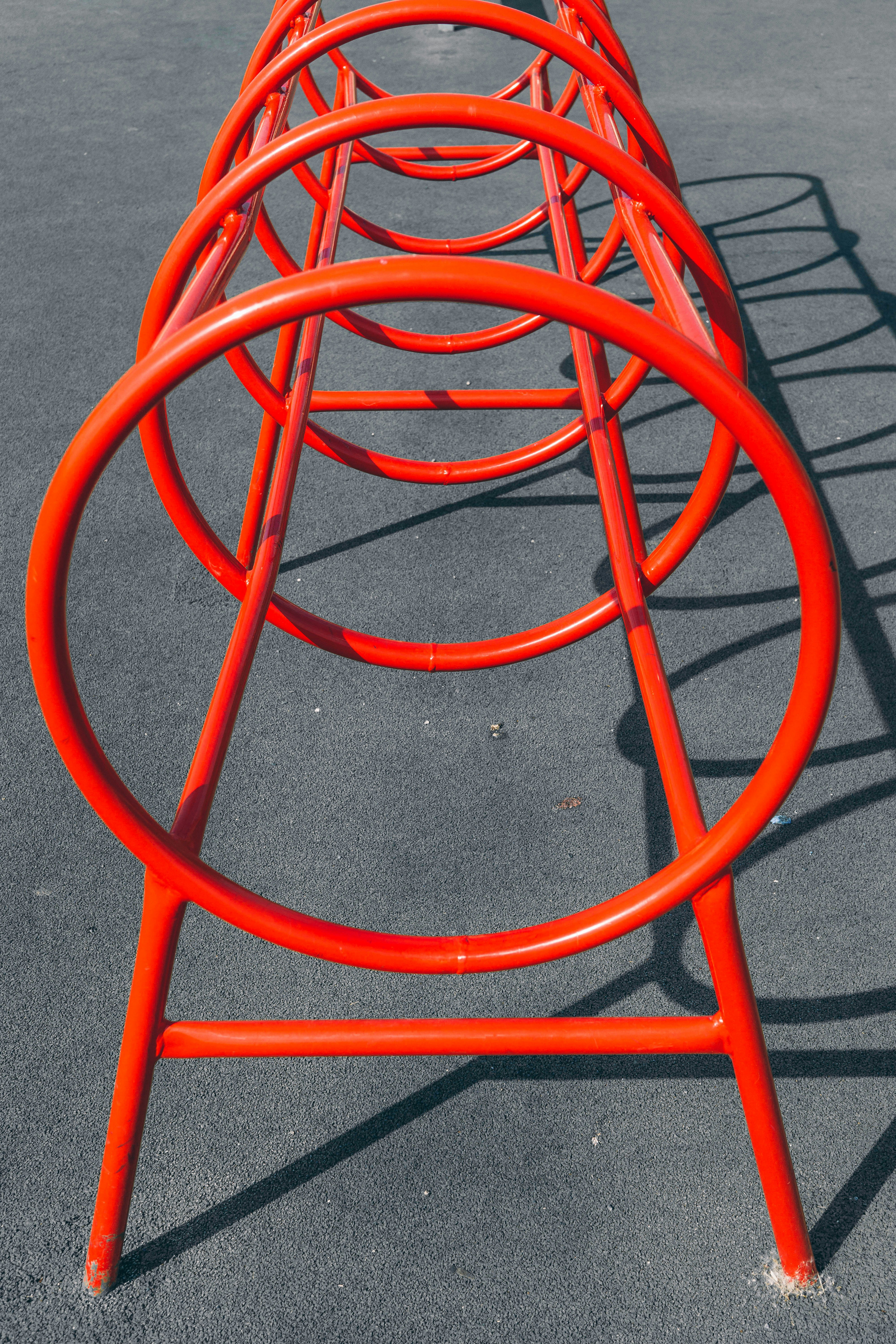 Red circular metal playground equipment on dark pavement.