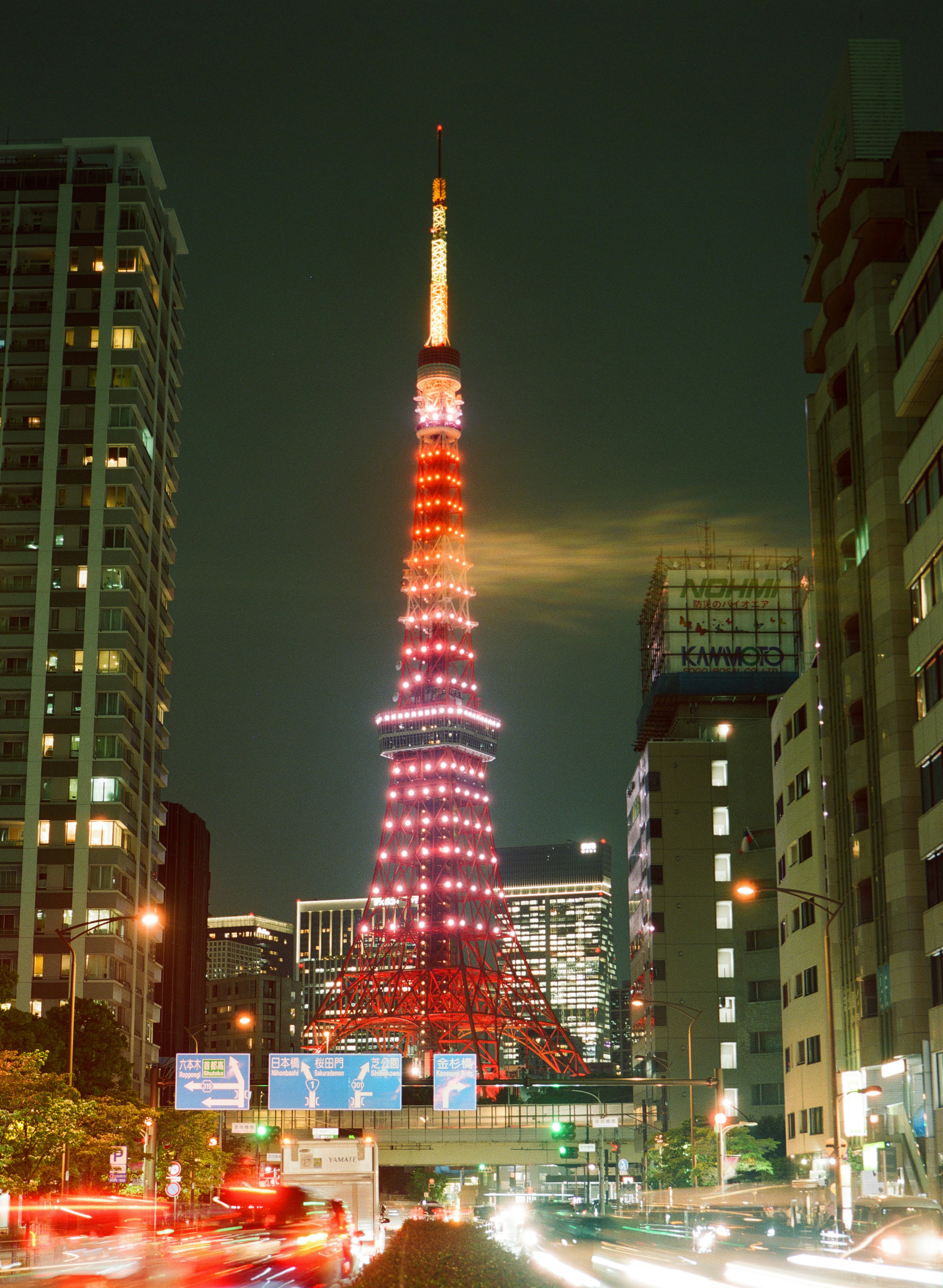 Iconic tokyo tower lit up at night with urban traffic