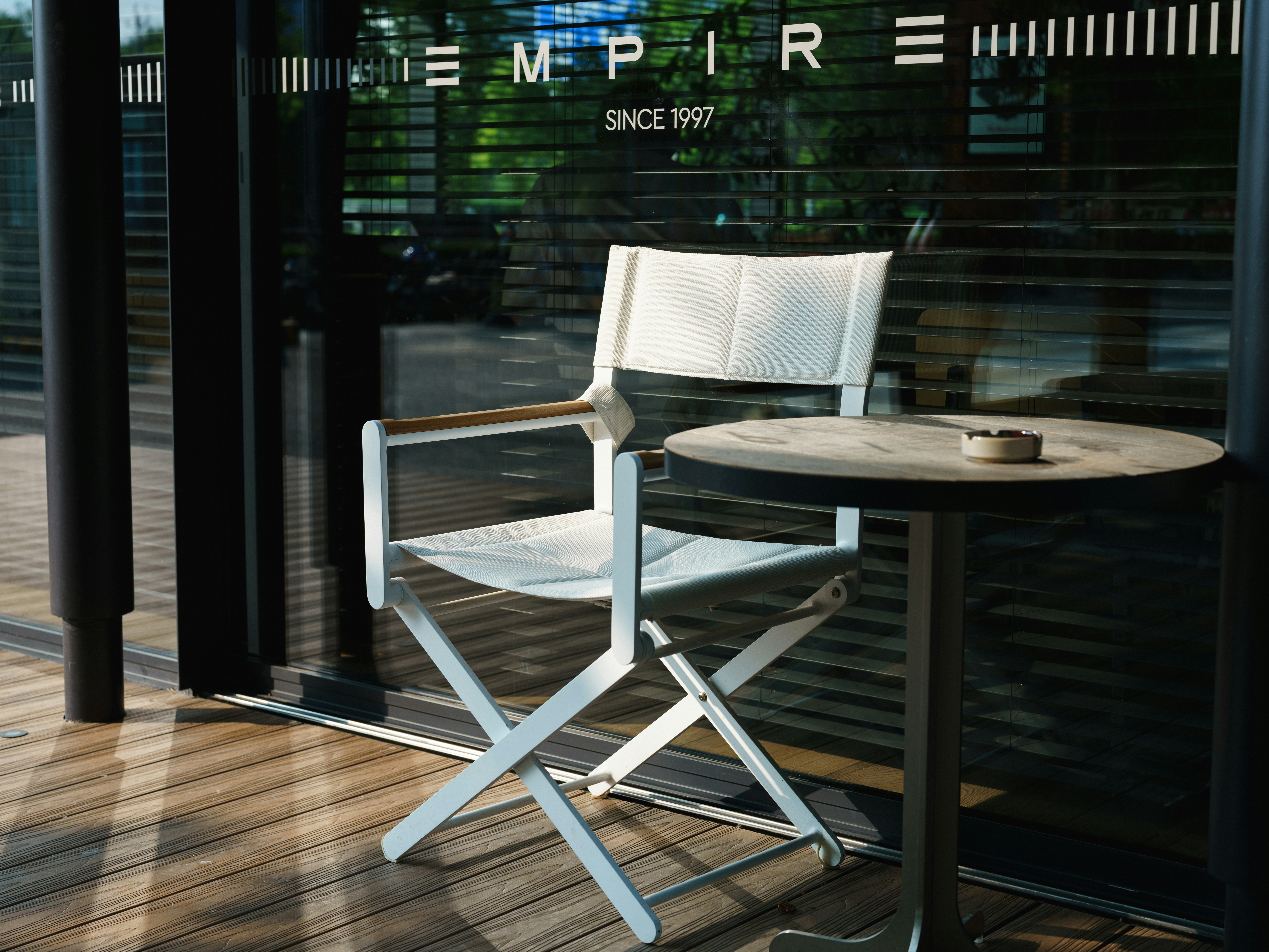 White folding chair and table with ashtray on a patio