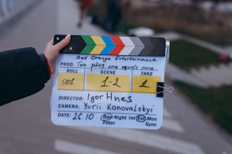 Hand holding a film clapperboard with production details outdoors