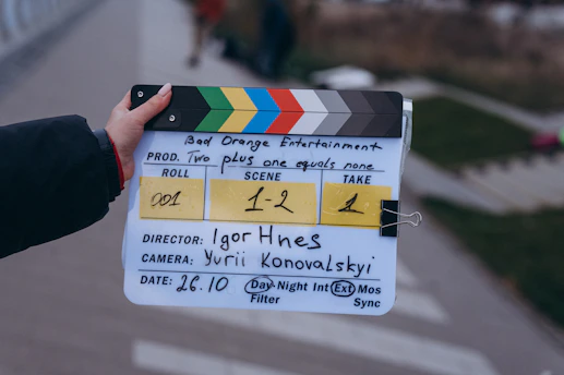 Hand holding a film clapperboard with production details outdoors