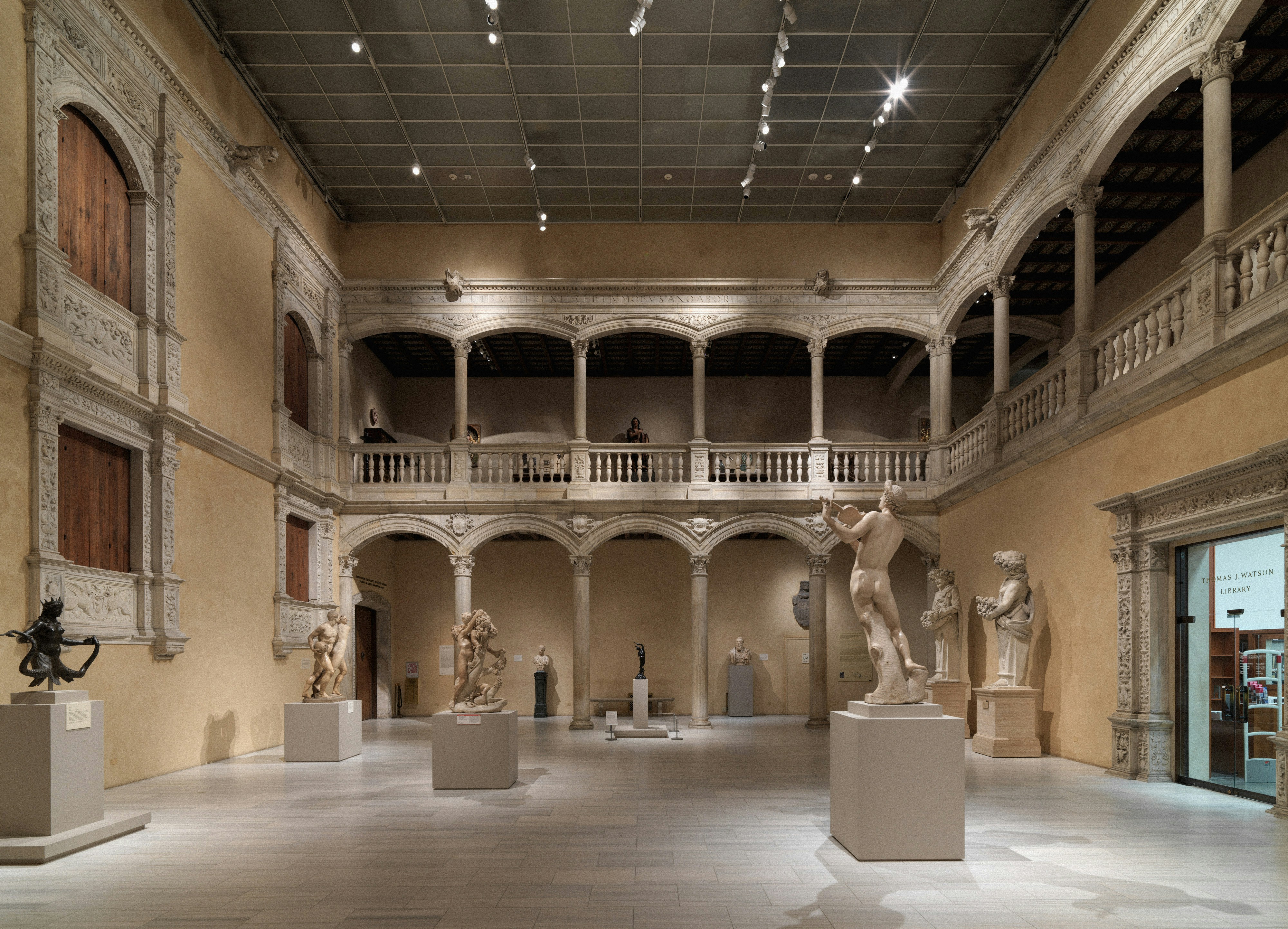Museum gallery with classical sculptures under arcaded balconies