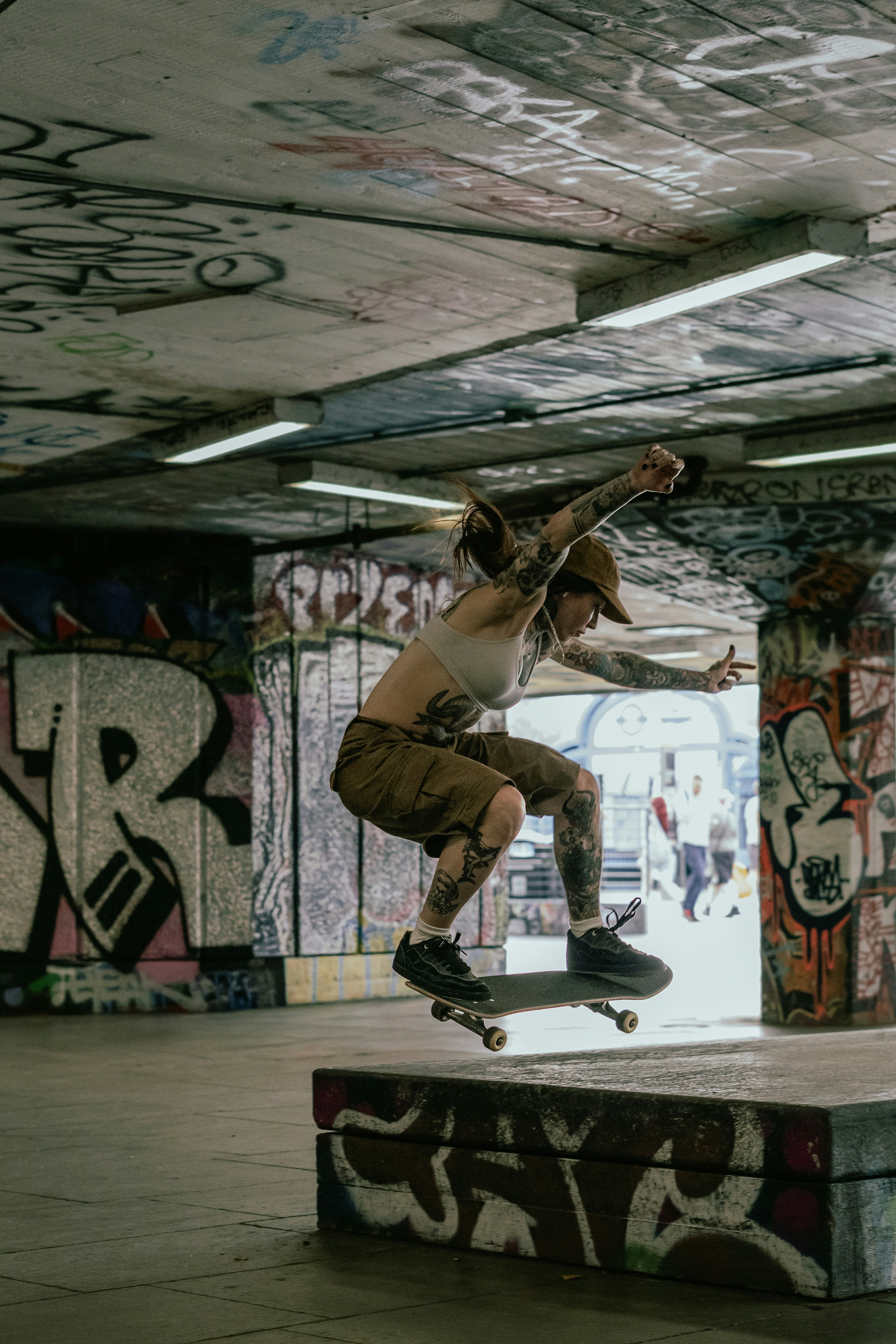 Skateboarder jumping over a ledge in a graffiti-covered underpass