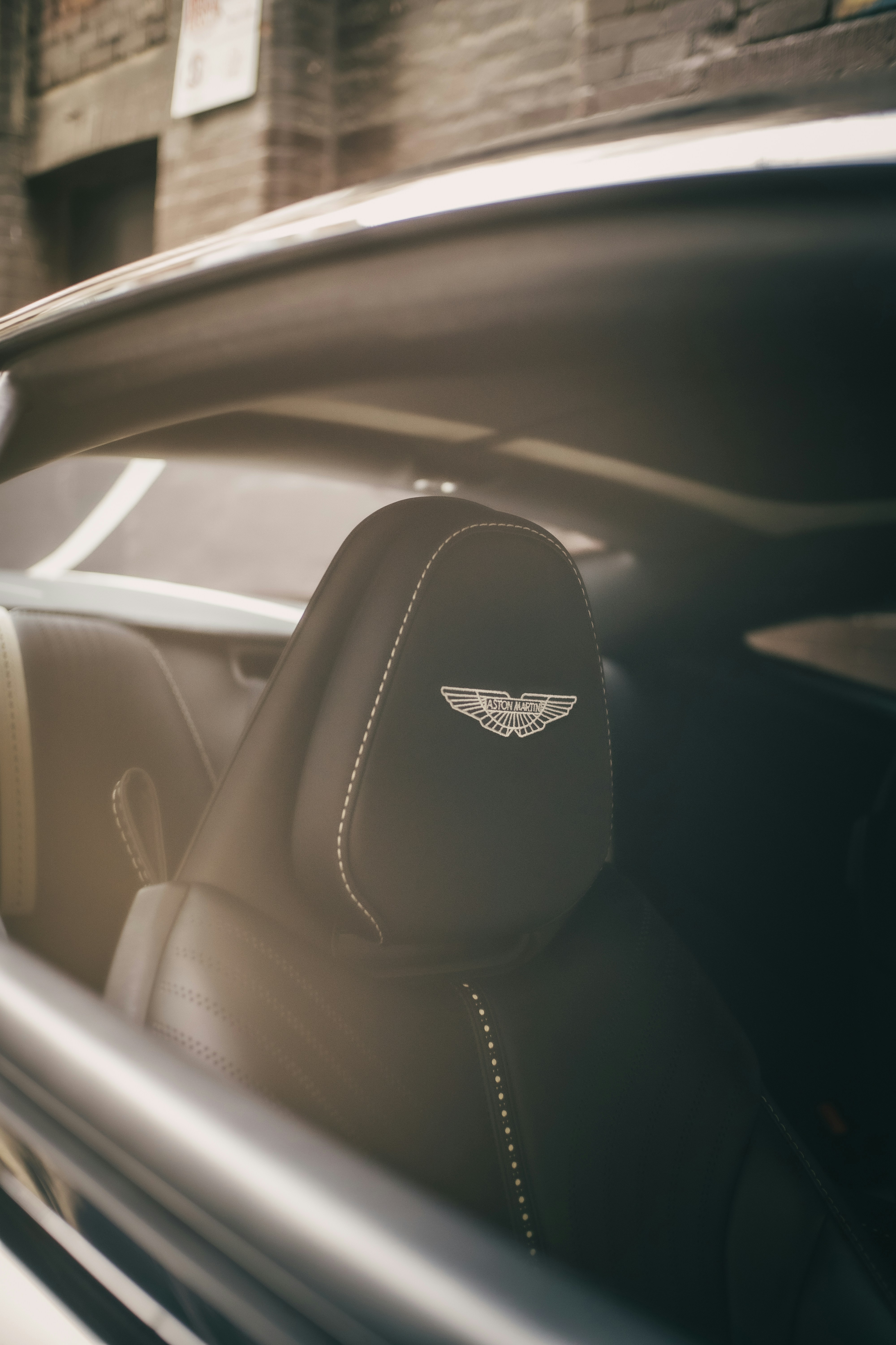 Siège auto en cuir noir avec le logo Aston Martin sur l’appuie-tête.