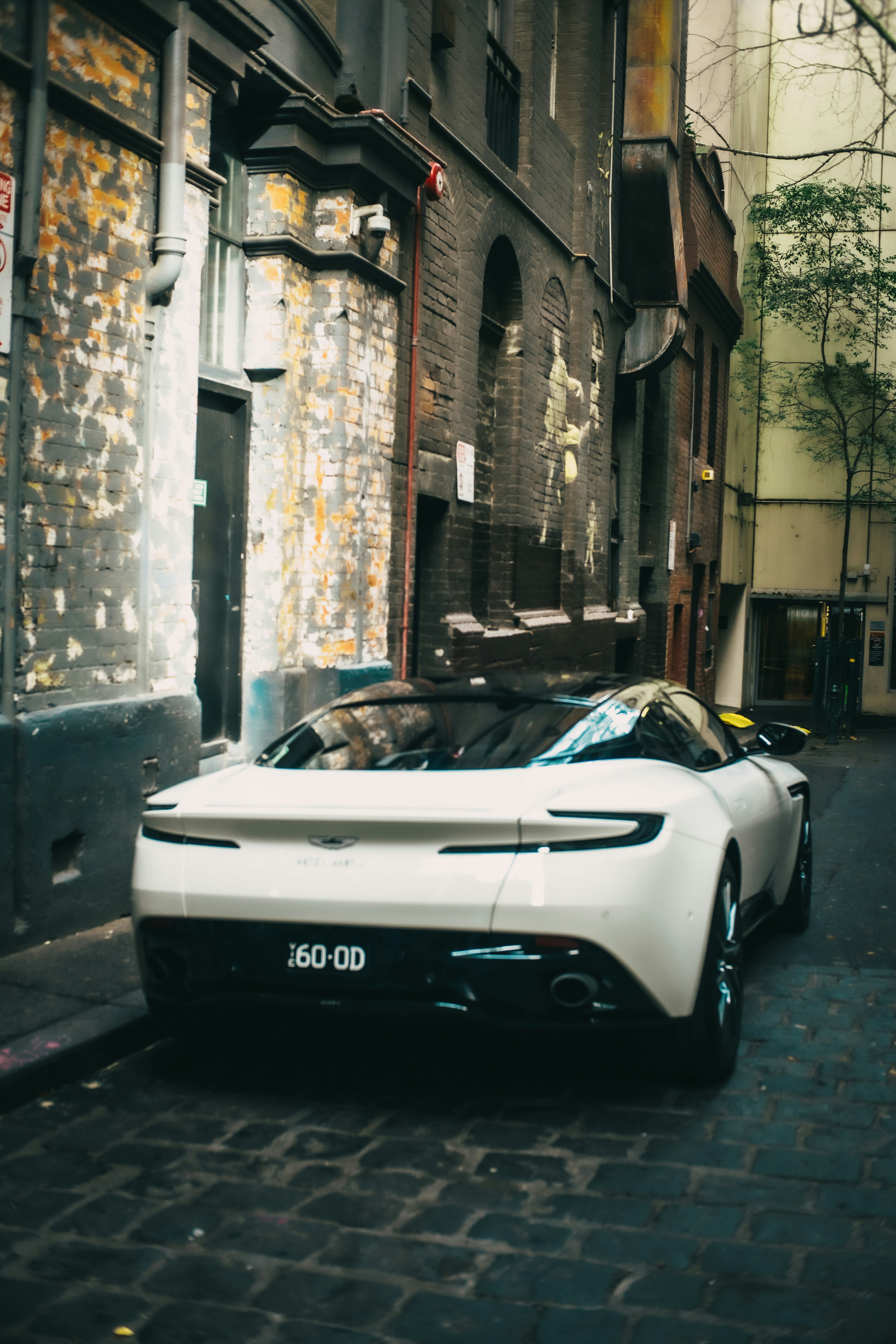 Une voiture de sport blanche élégante garée dans une ruelle urbaine miteuse.