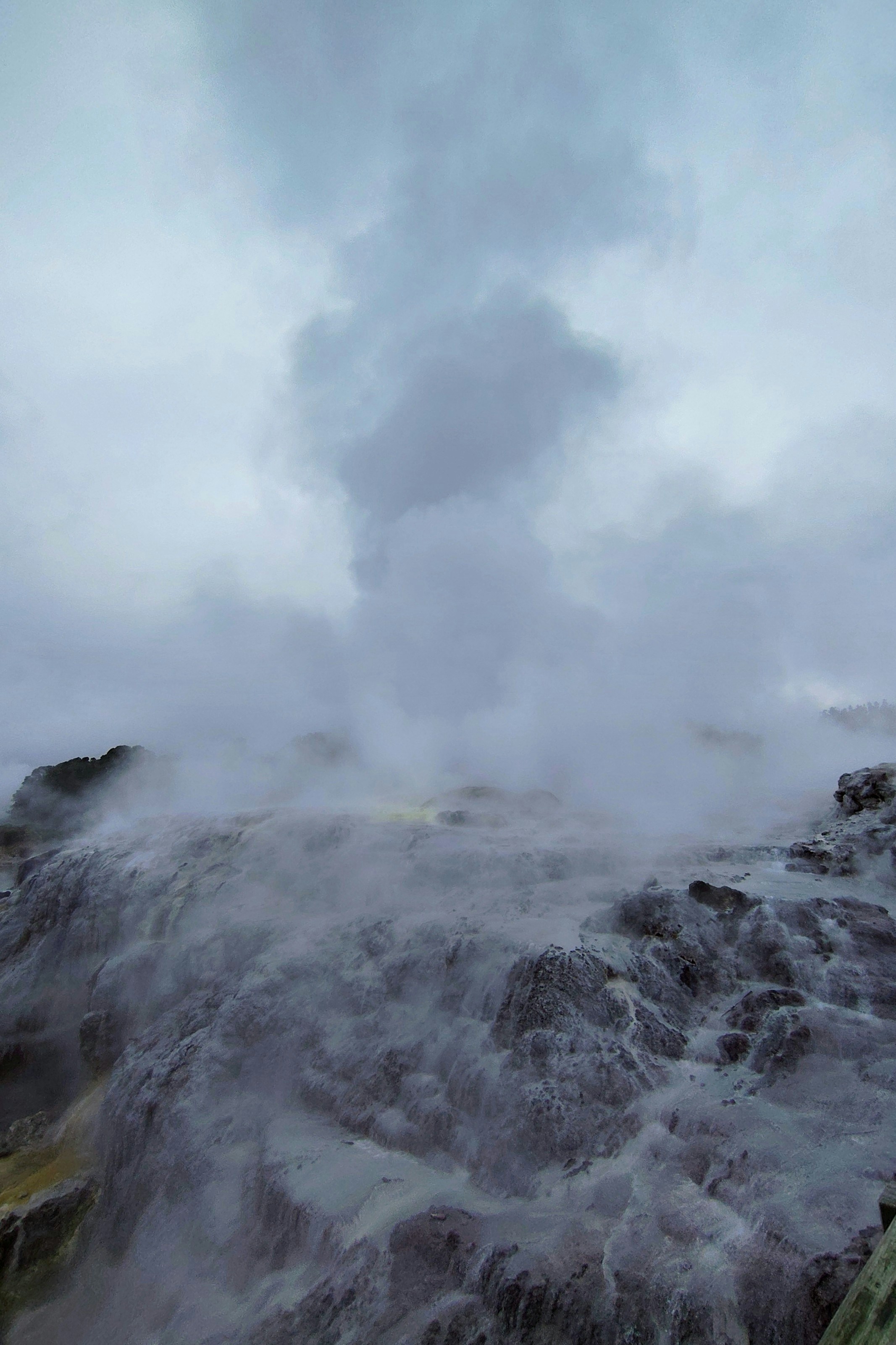 Volcanic landscape with steam rising under a cloudy sky