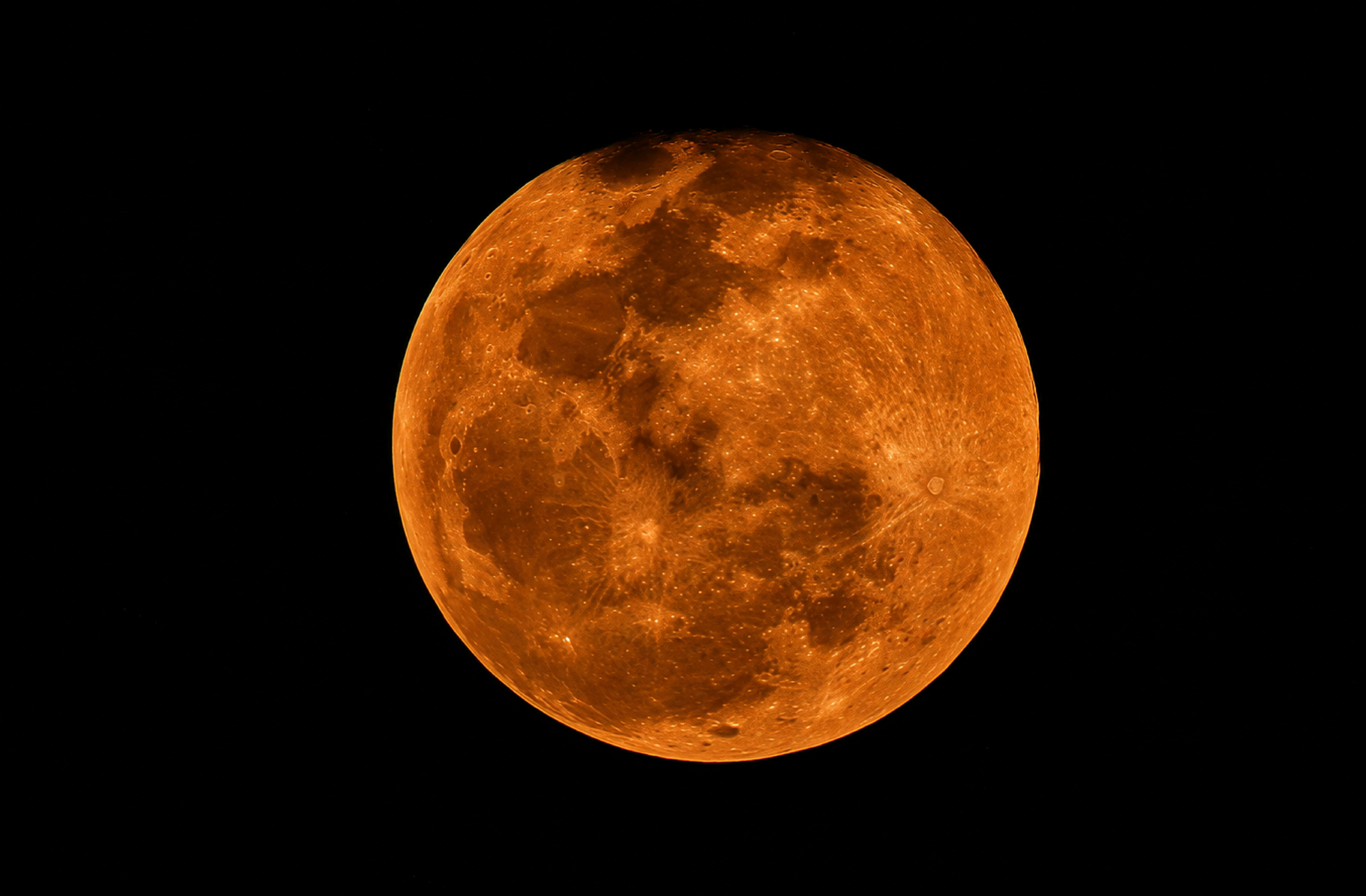 A large orange full moon against a dark night sky.