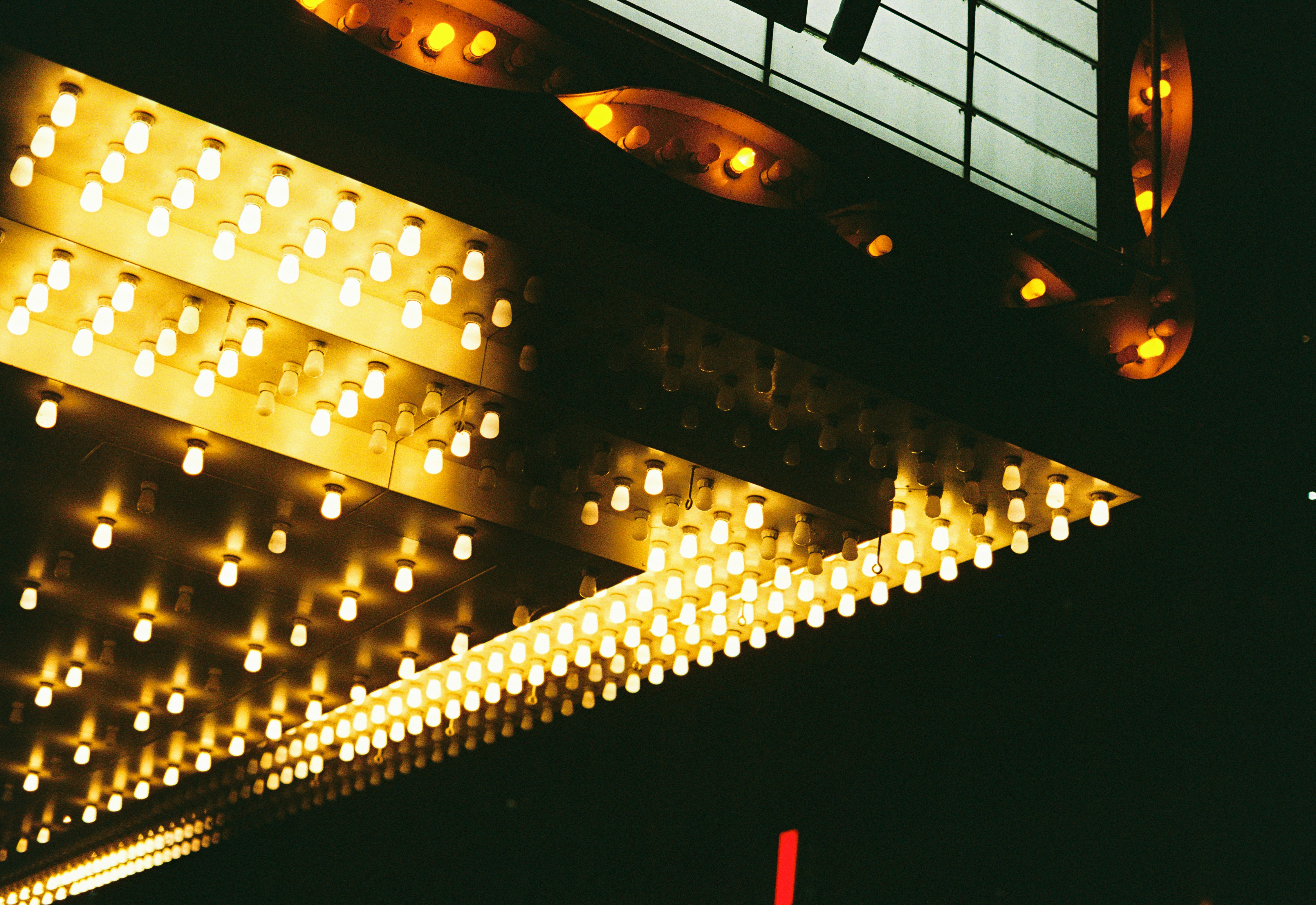 Bright yellow lights illuminate a sign at night.