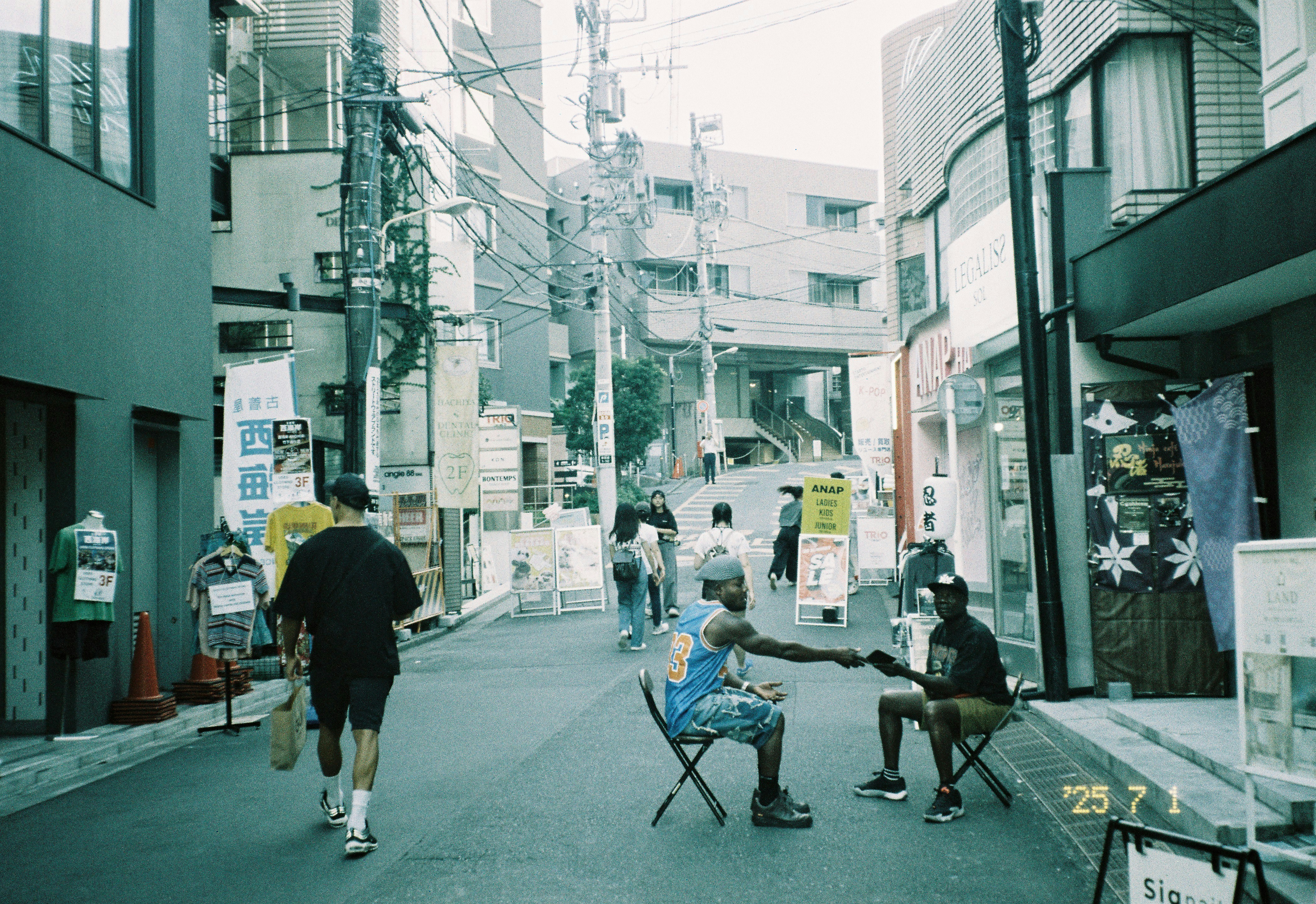 Two men playing guitar on a narrow city street.