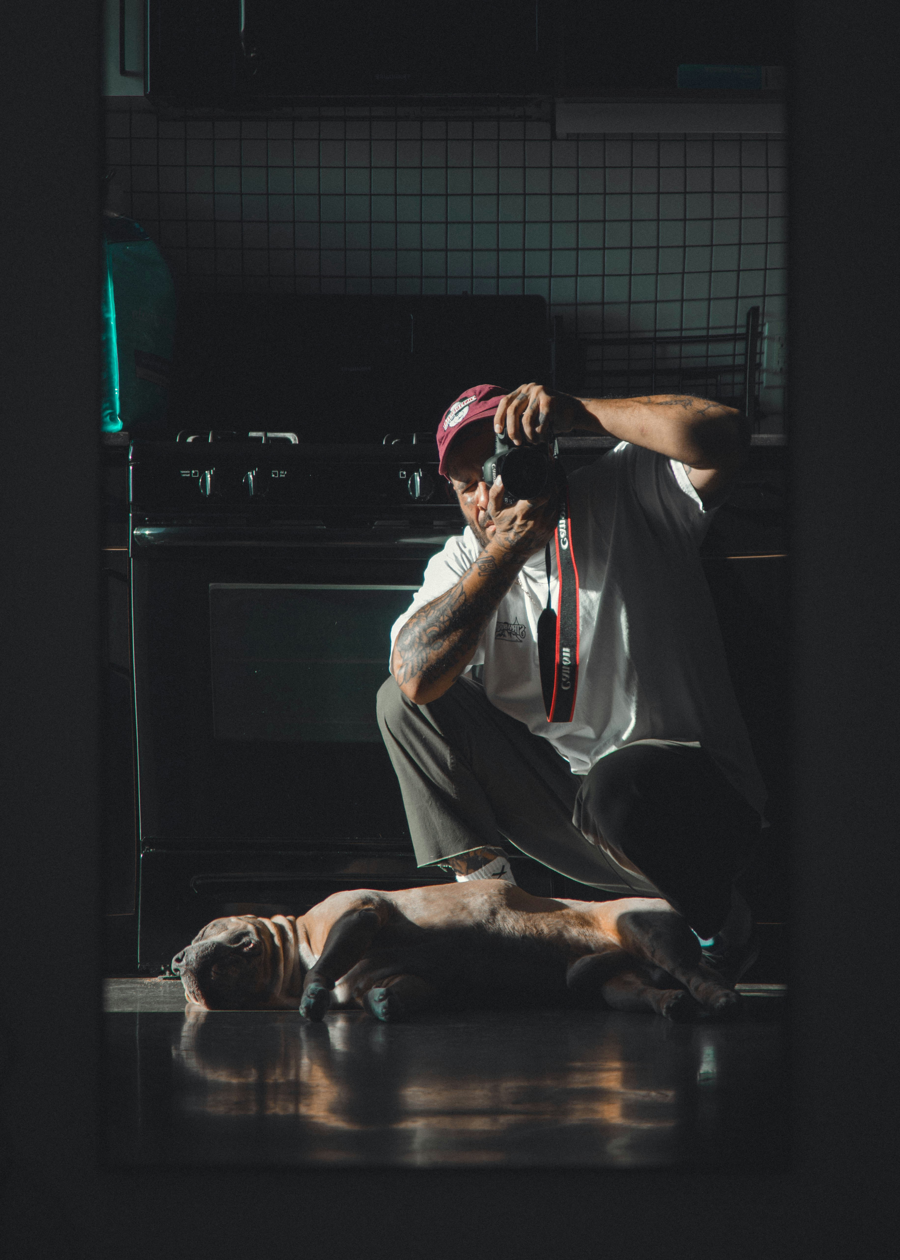 Un hombre fotografía a un perro dormido iluminado por la luz del sol en el interior.