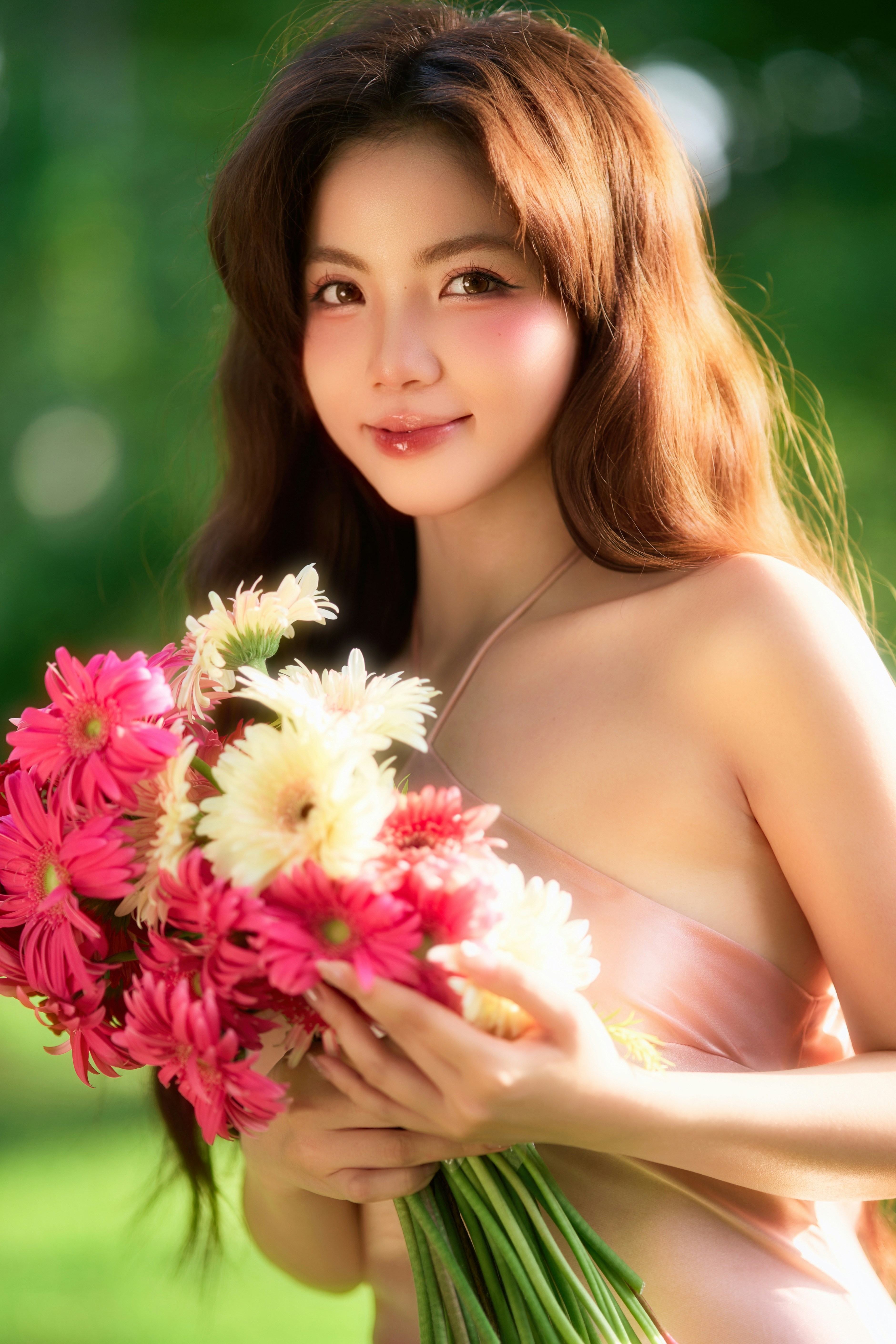 Woman holding vibrant pink and white flowers, smiling outdoors.