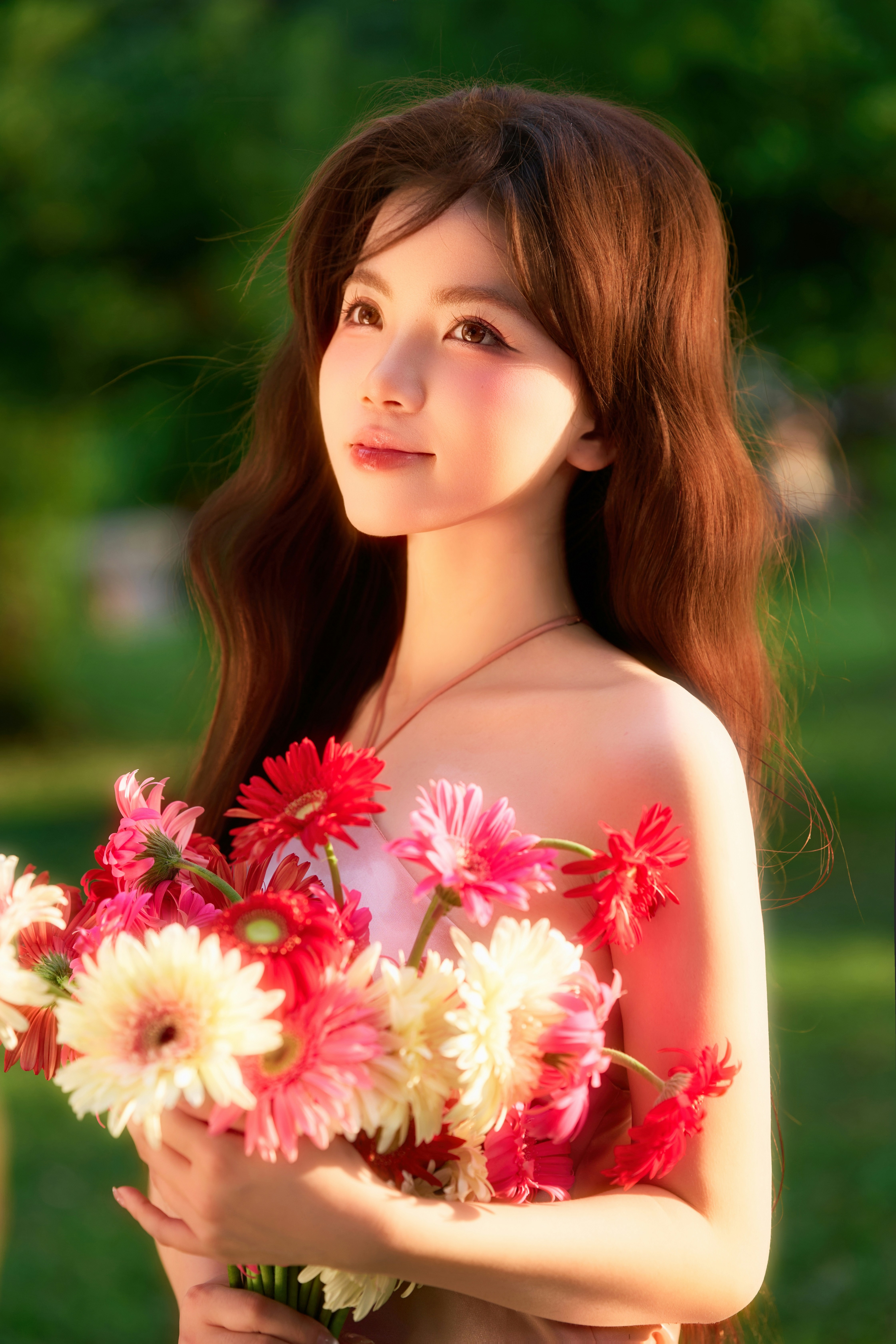 A young woman holding colorful flowers in a sunny garden.
