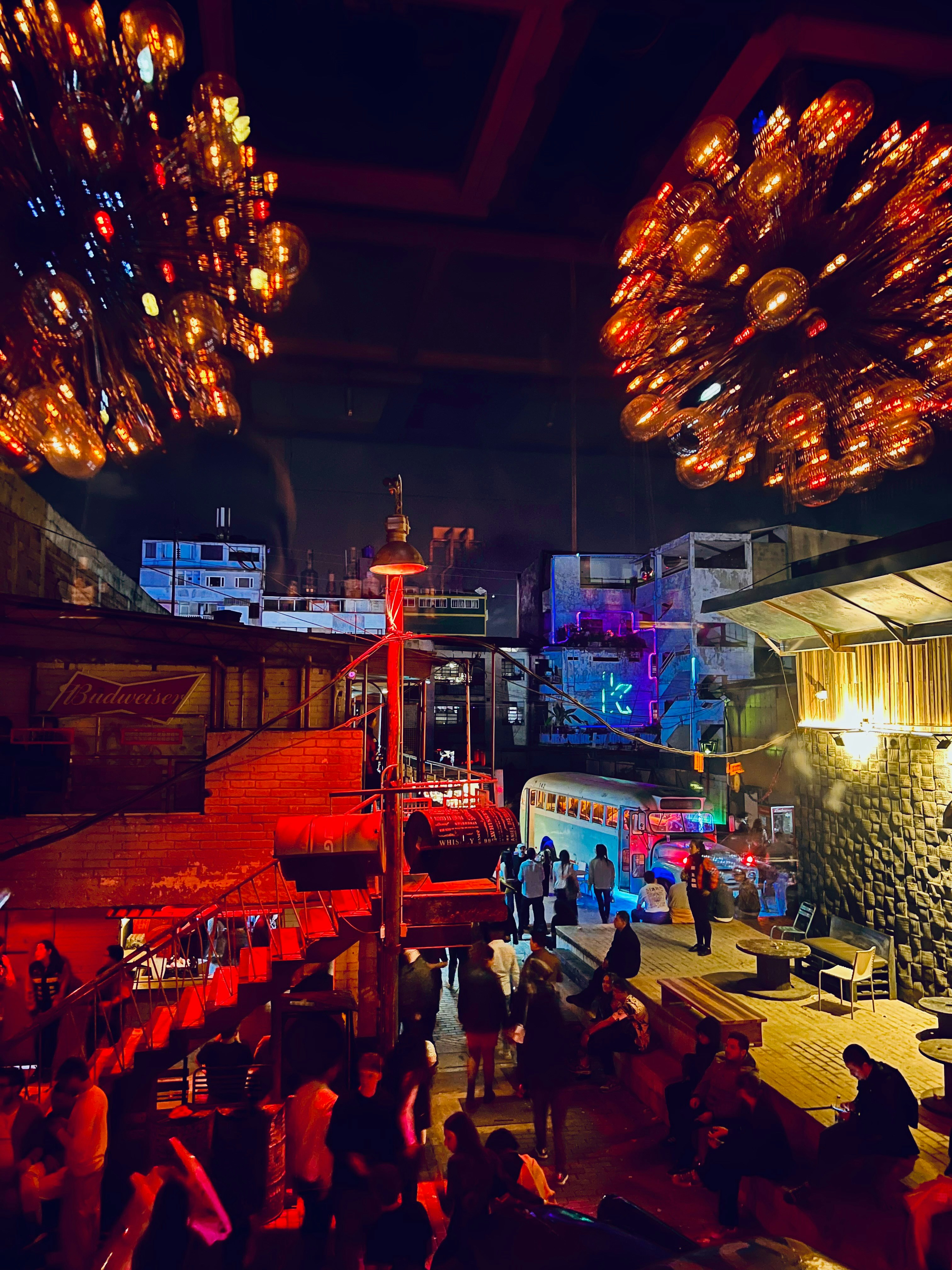 Crowded multi-level bar at night with sparkling chandeliers