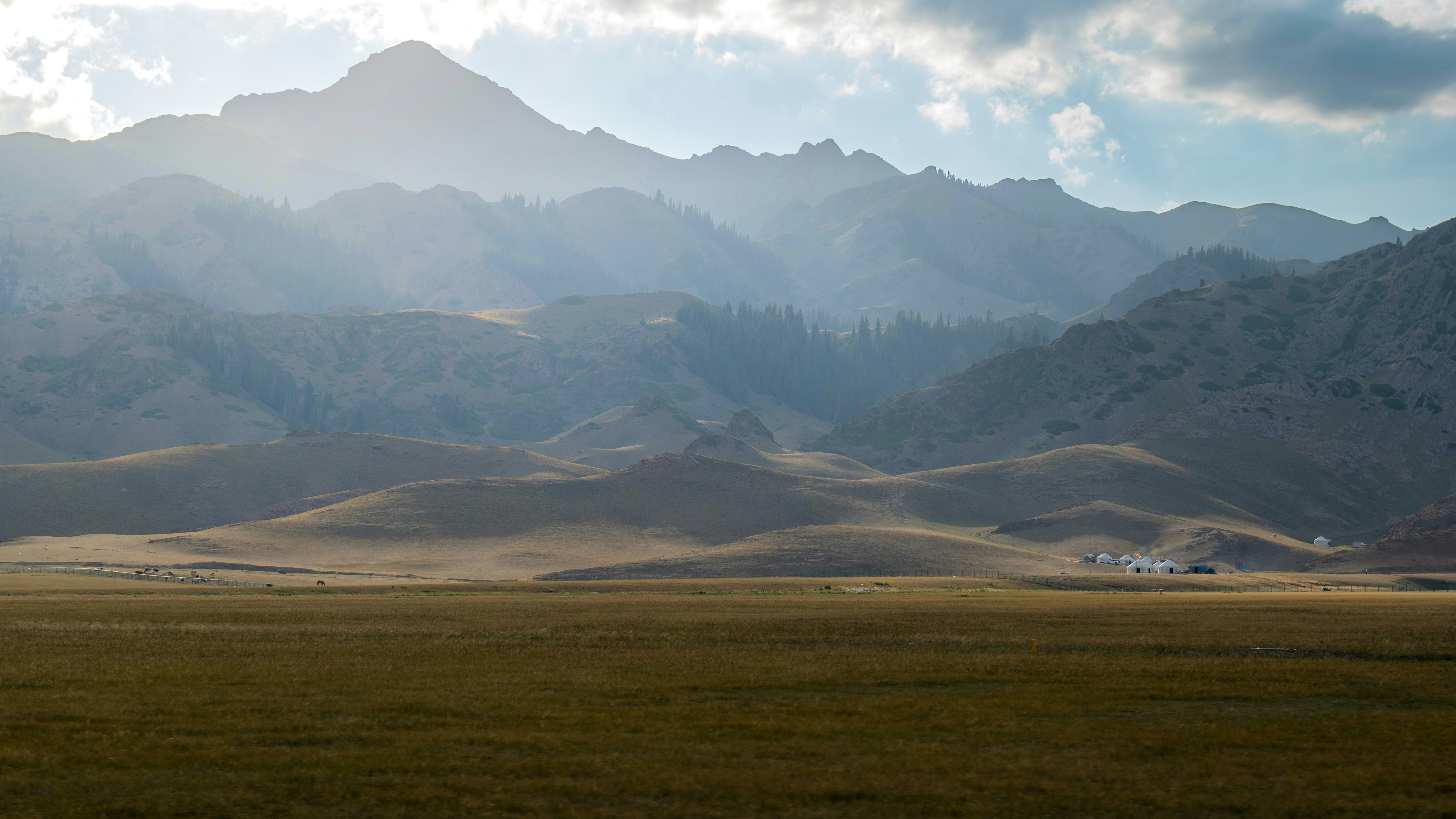 Hazy mountains rise above a vast grassy plain - Free Photo on Unsplash