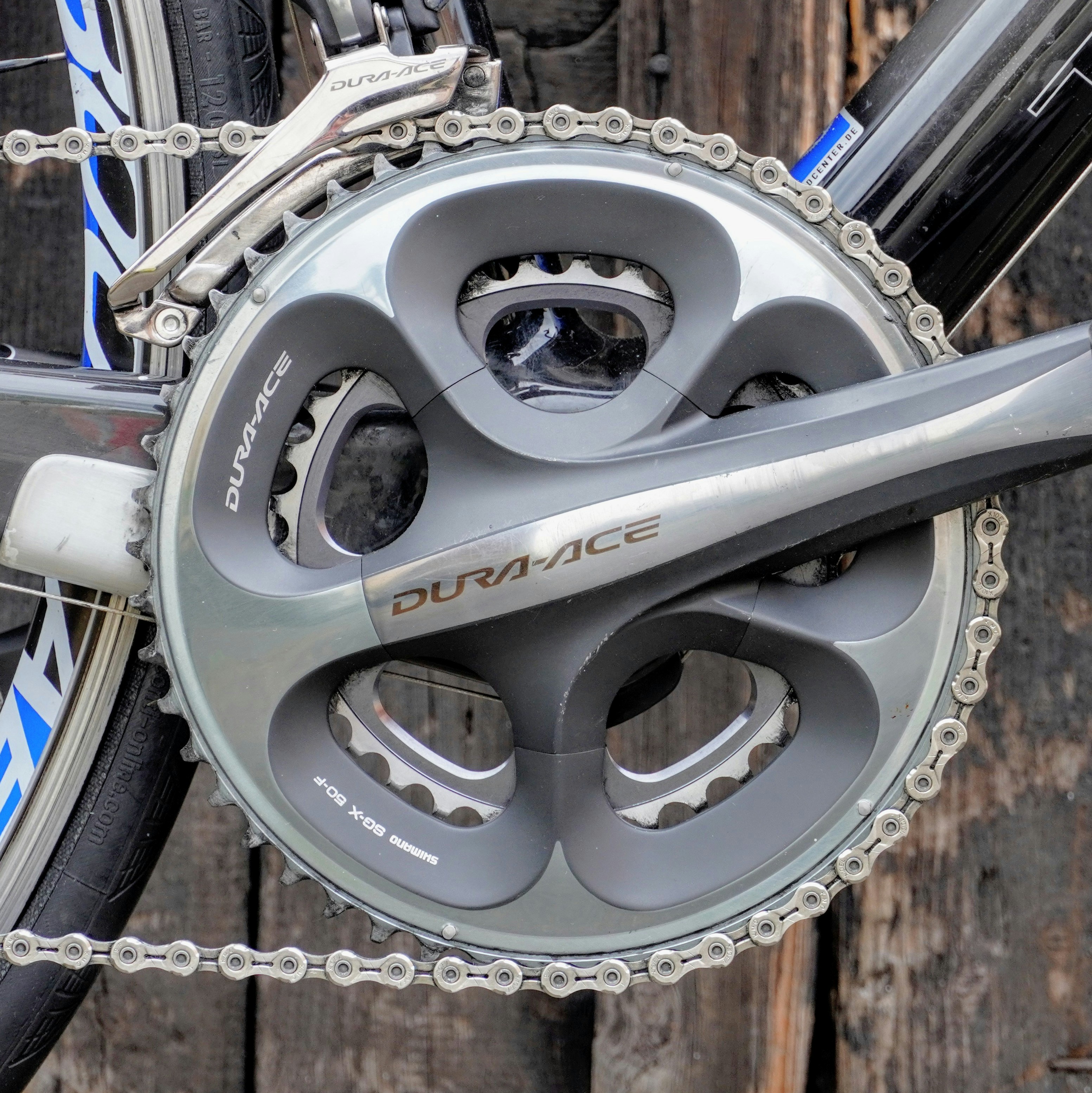 A bicycle's crankset and chain against a wooden background
