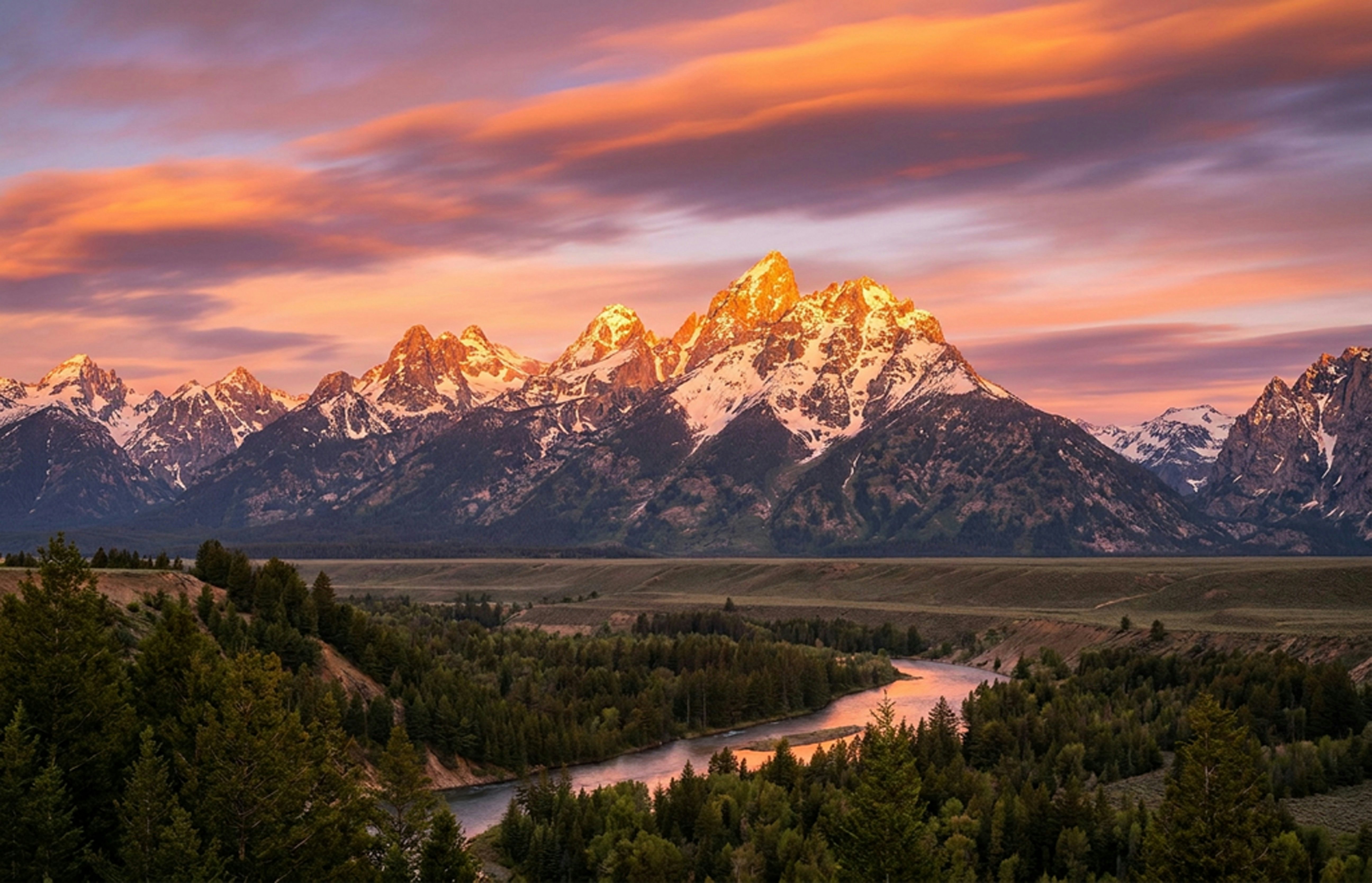 Vibrant sunset over snowy mountains and a winding river