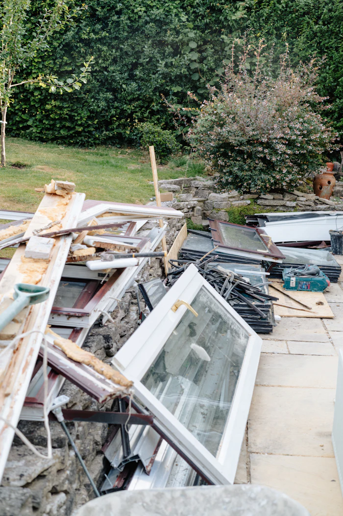 Discarded window frames and renovation waste stacked in a back yard