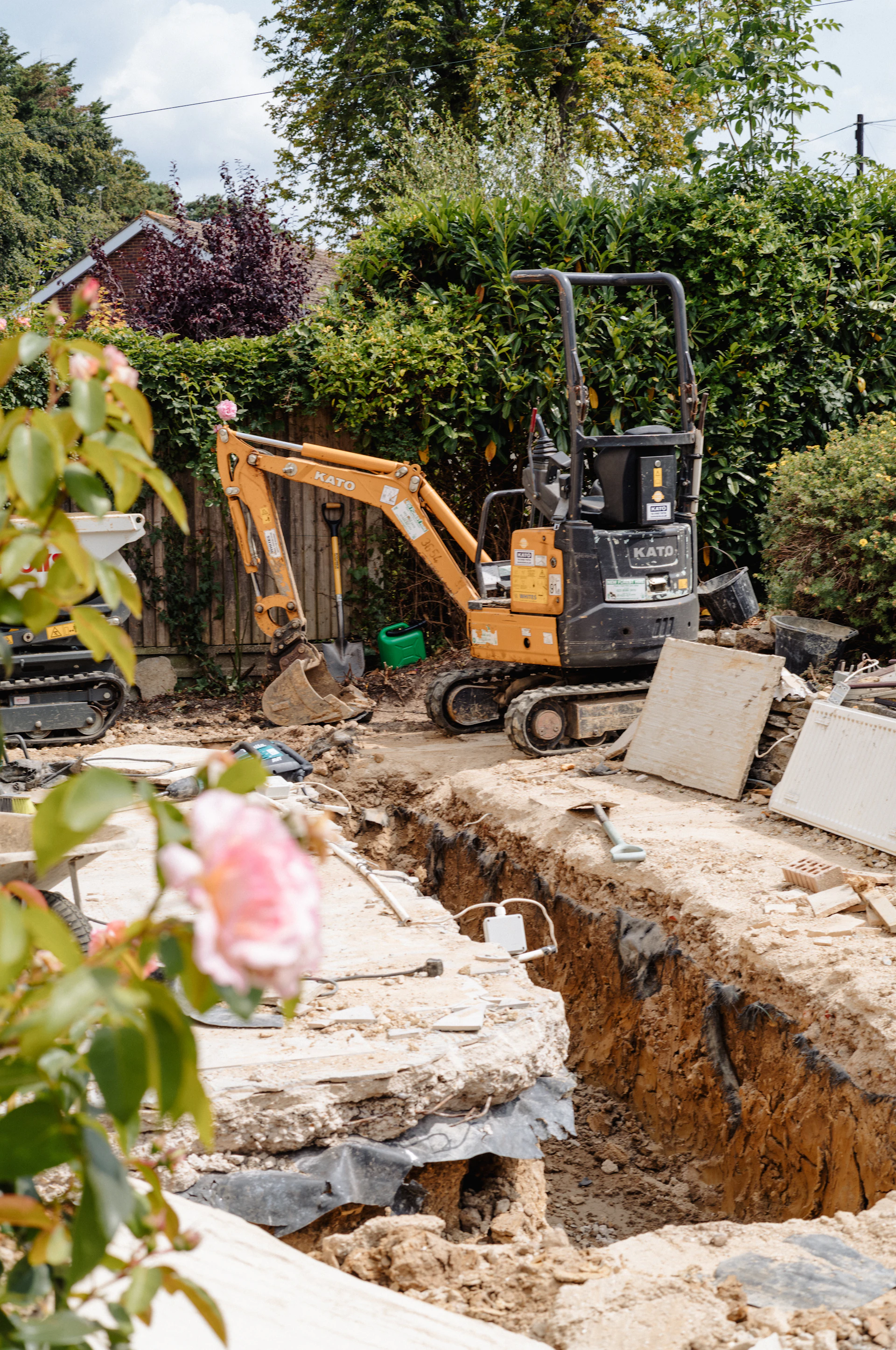Mini excavator cutting foundations in a back garden