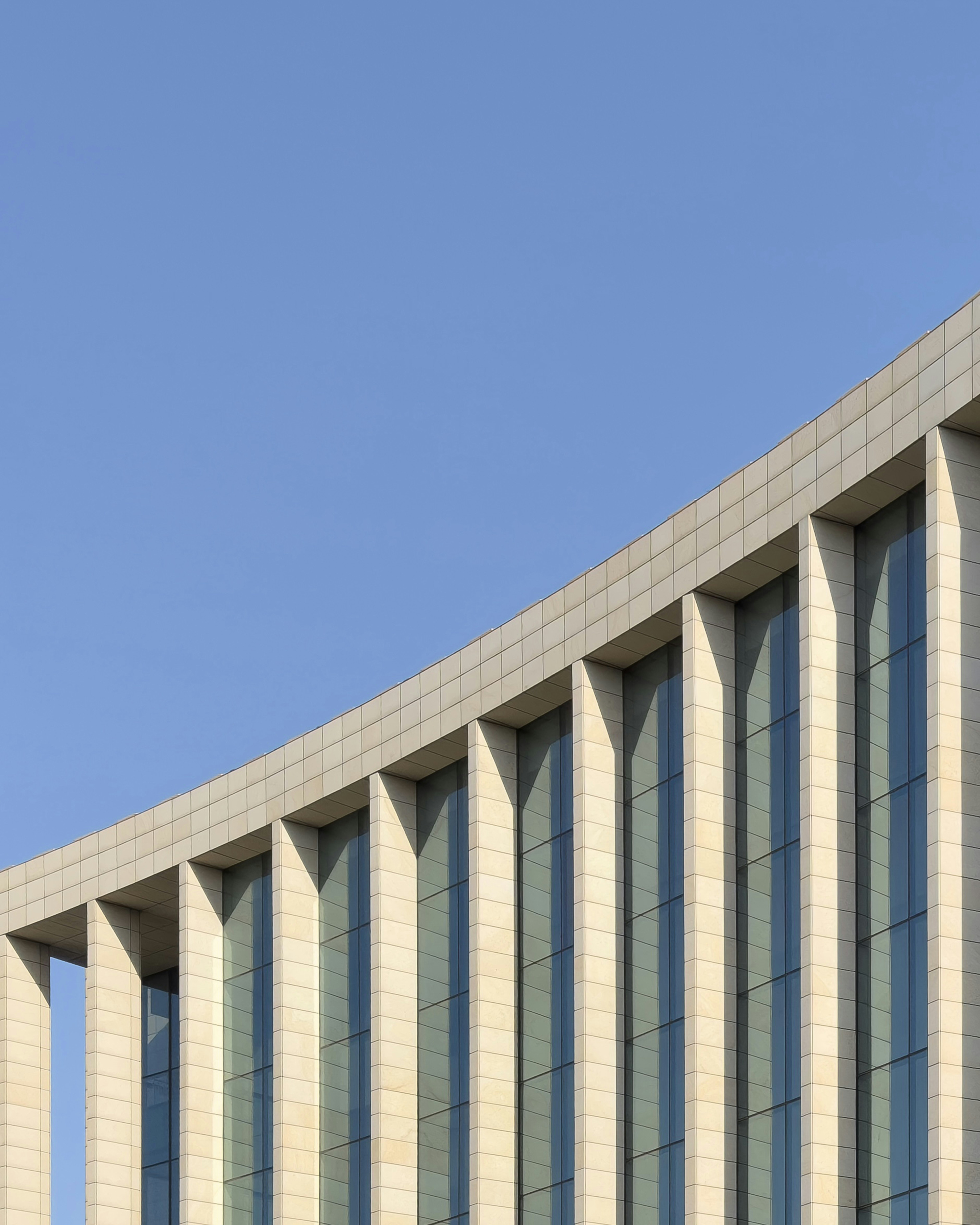 Curved modern building facade with stone columns and glass windows.