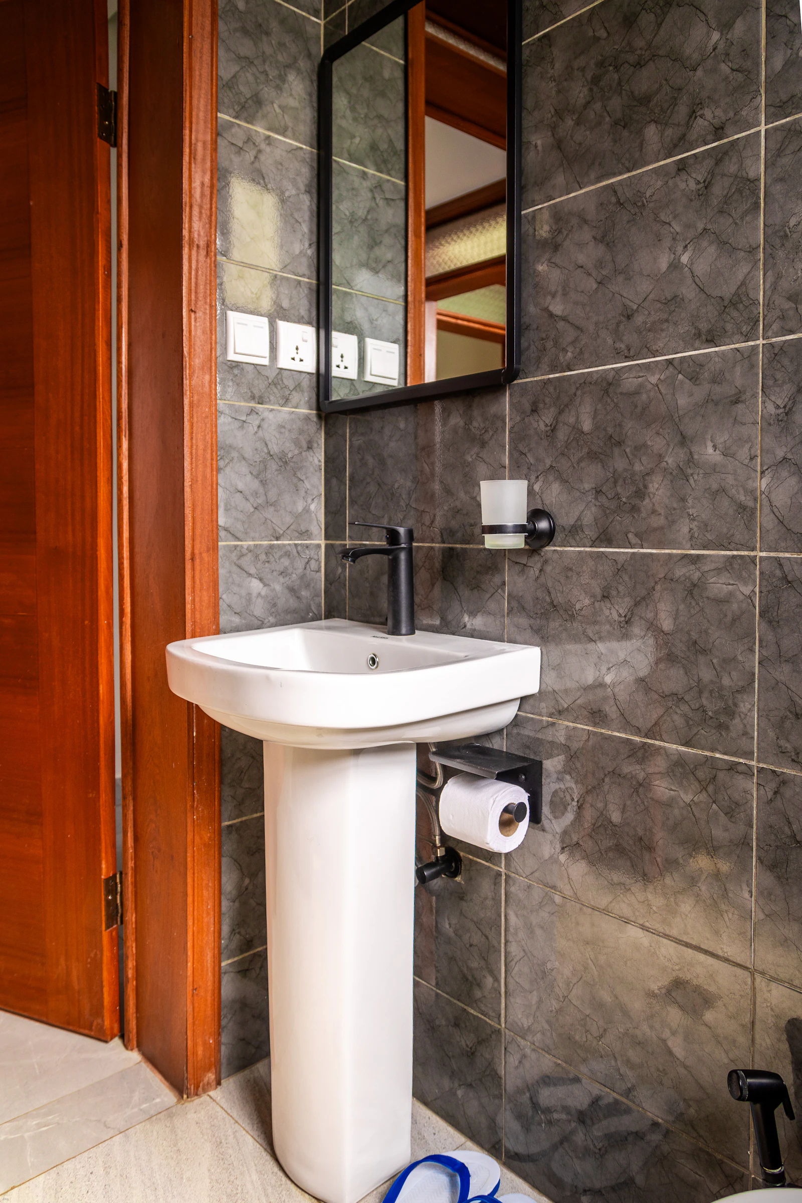 A modern bathroom vanity with a white pedestal sink, black faucet, and large mirror