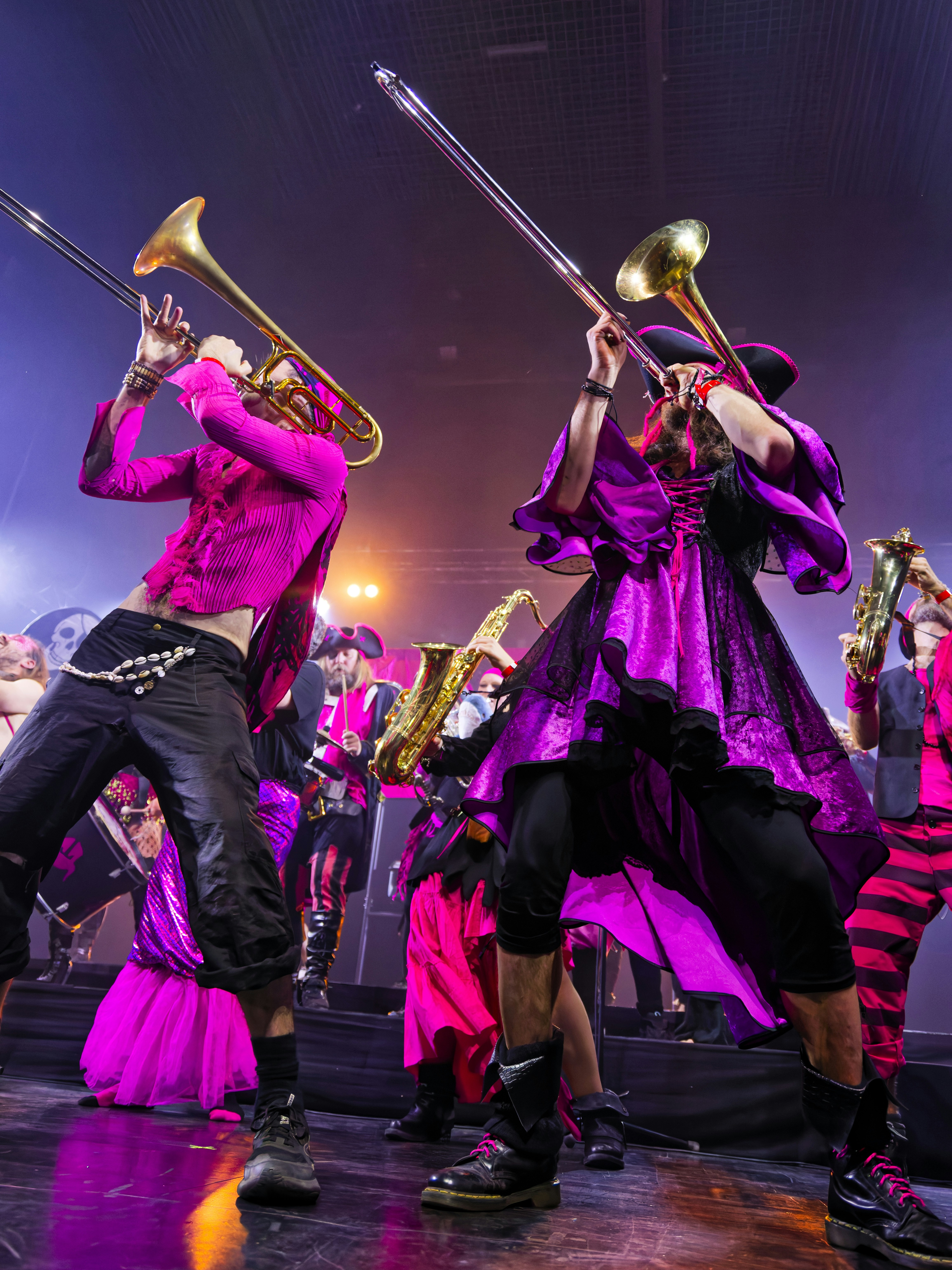 Vibrant musicians in pink costumes playing brass instruments on stage