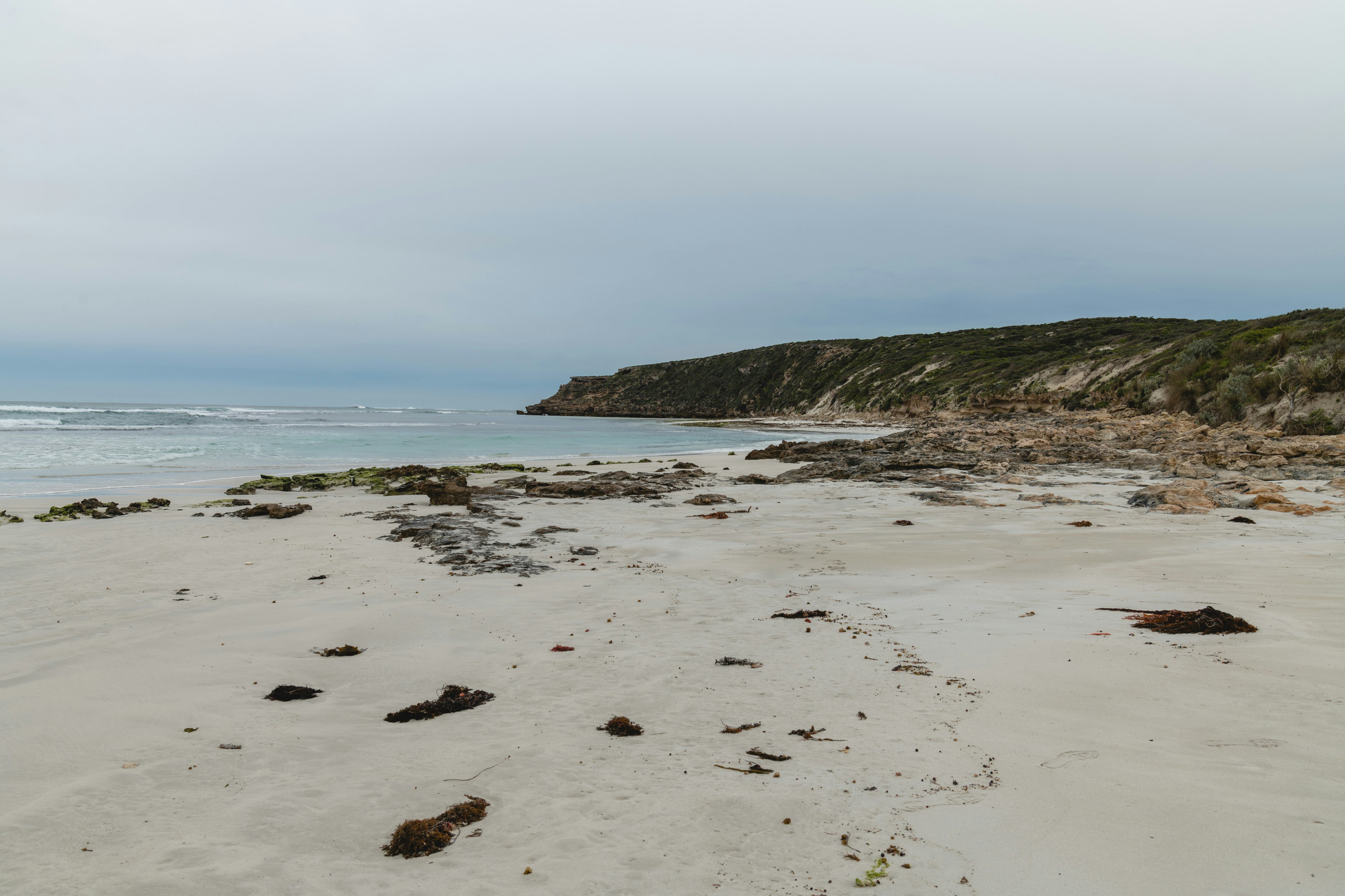 Sandy beach with rocky coastline under an overcast sky