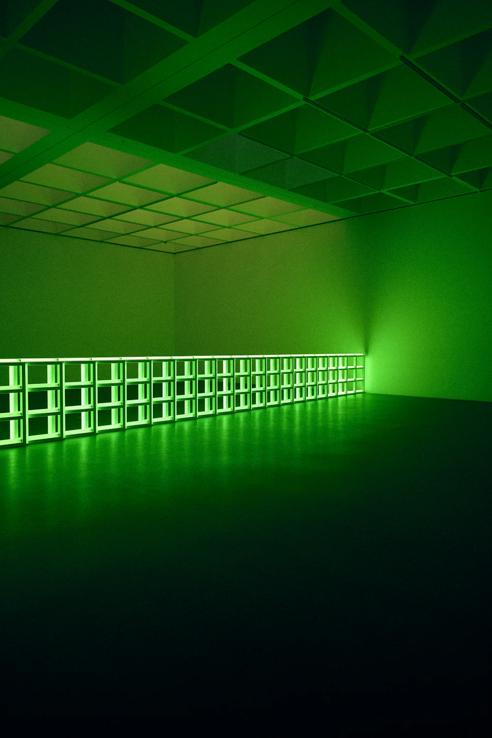 A long green light glowing in a dark room.