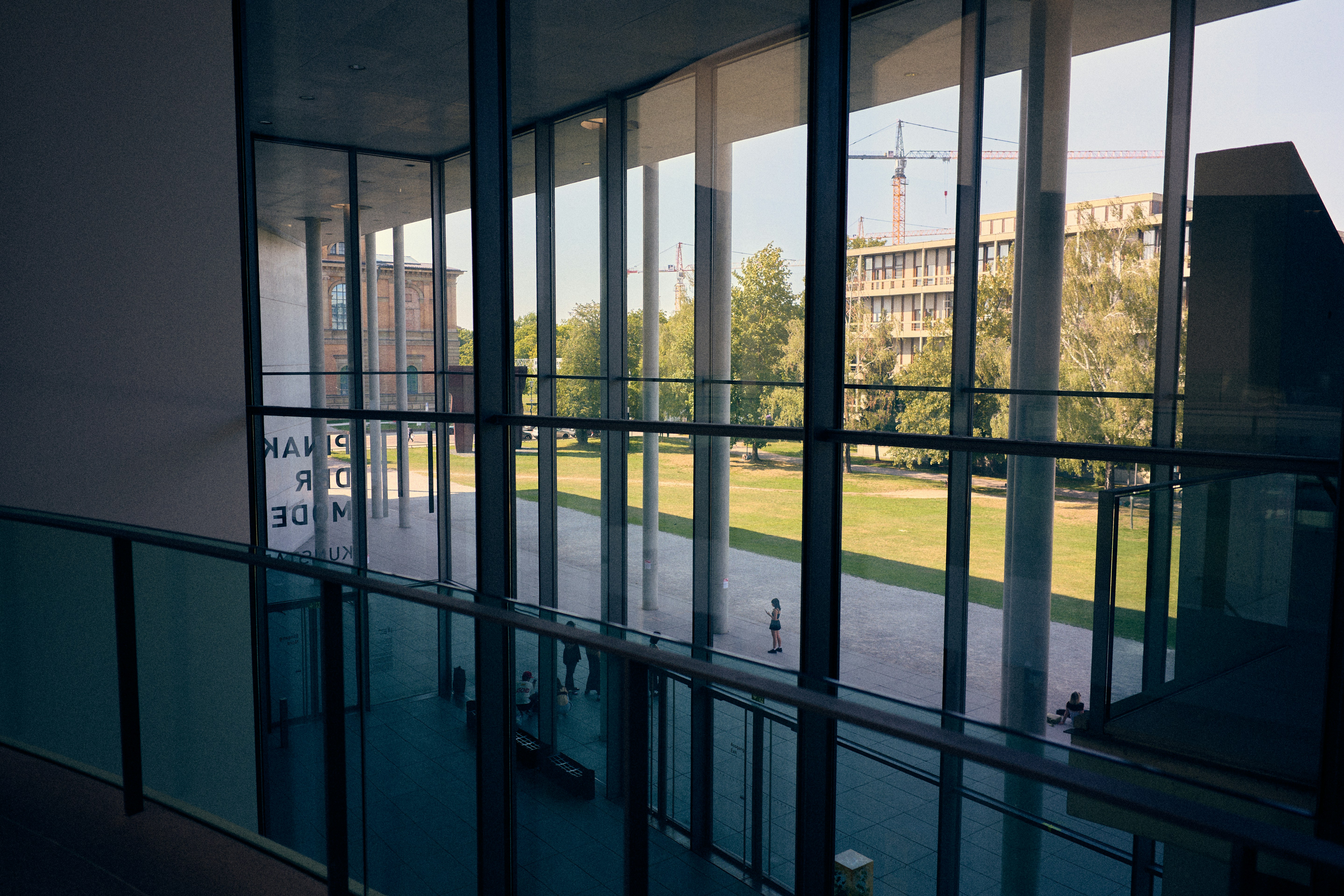 People moving through a contemporary public courtyard beside a park