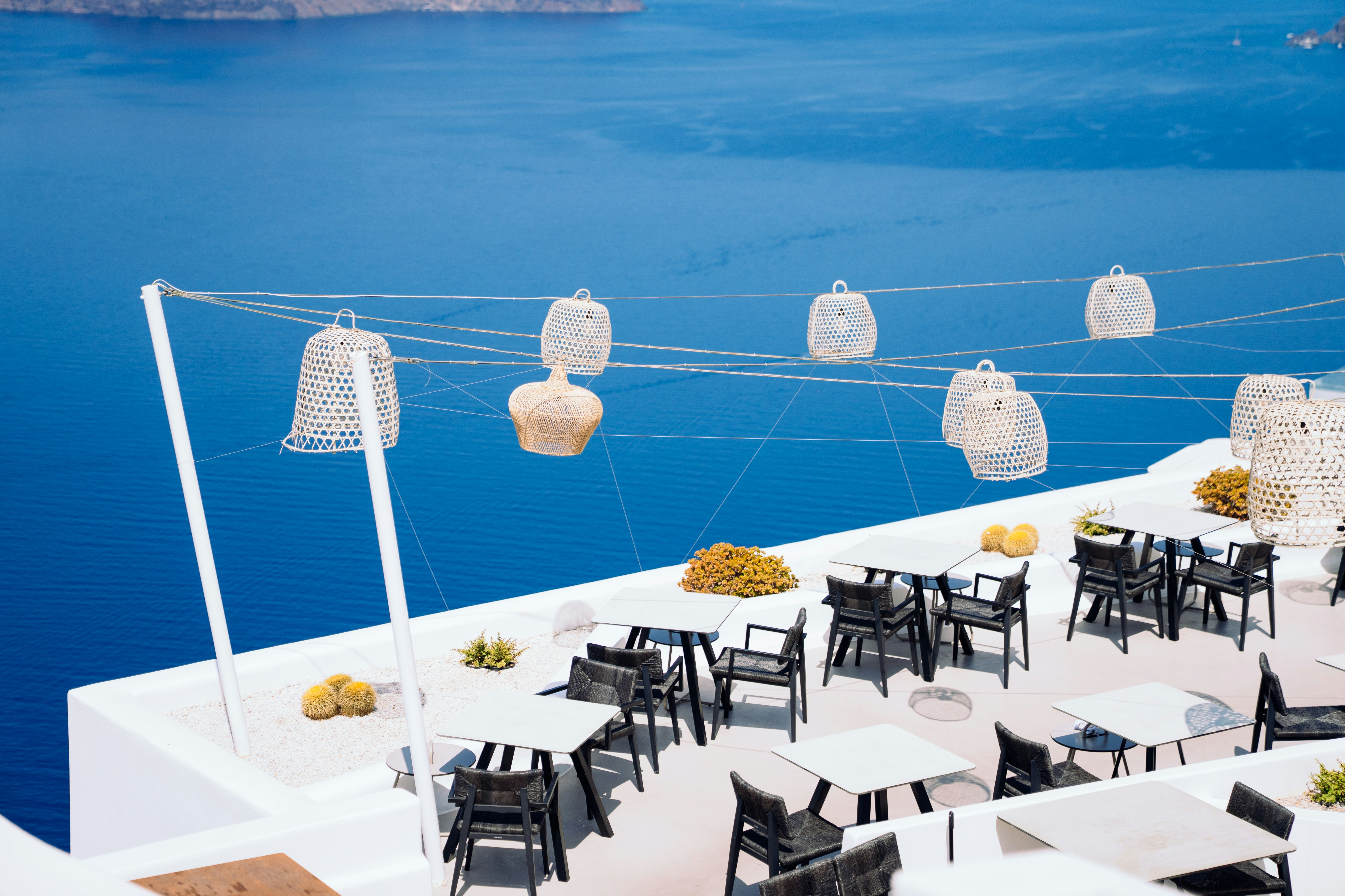 White terrace restaurant with lanterns overlooking a blue sea