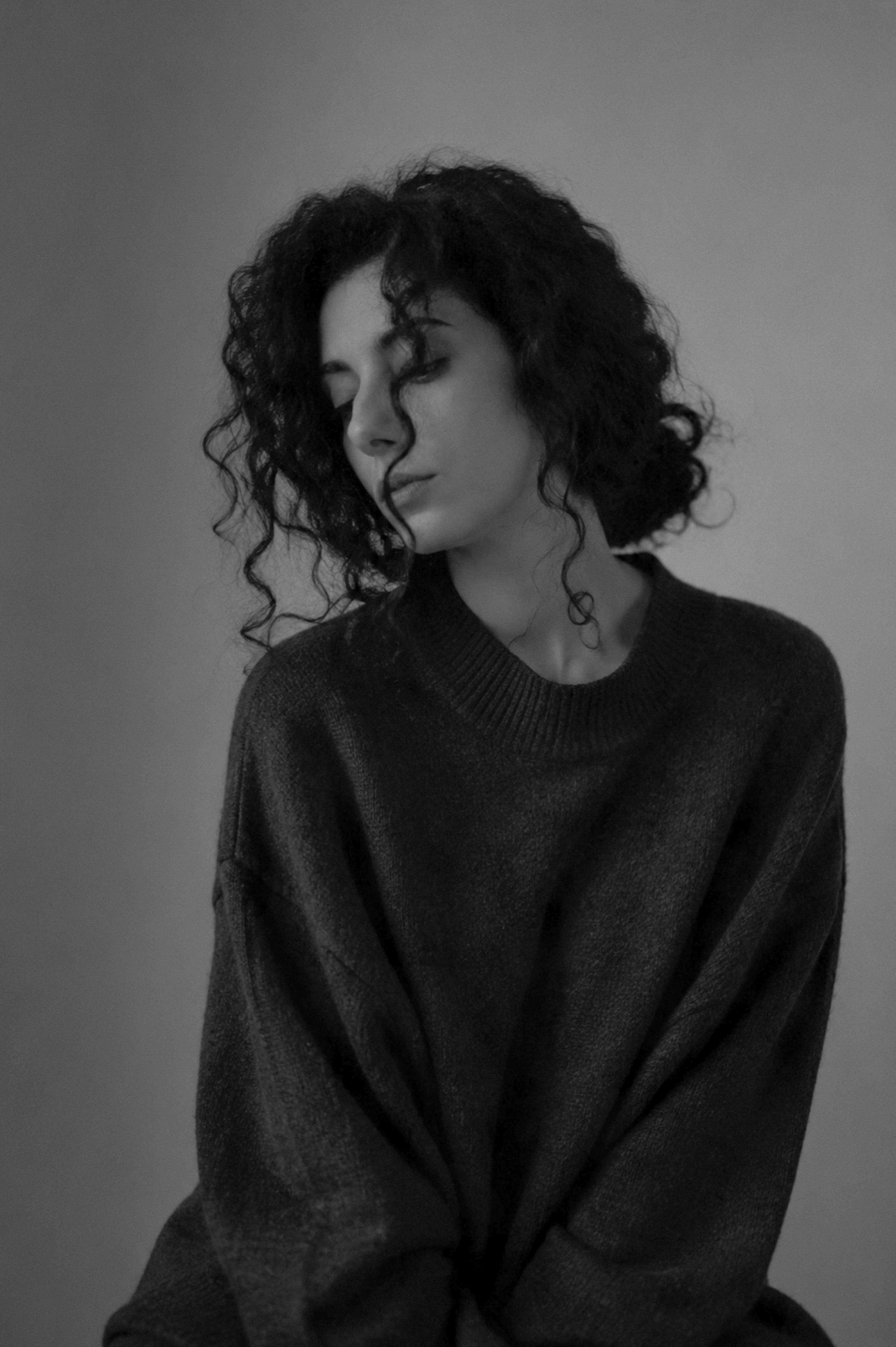 Woman with curly hair wearing a dark sweater