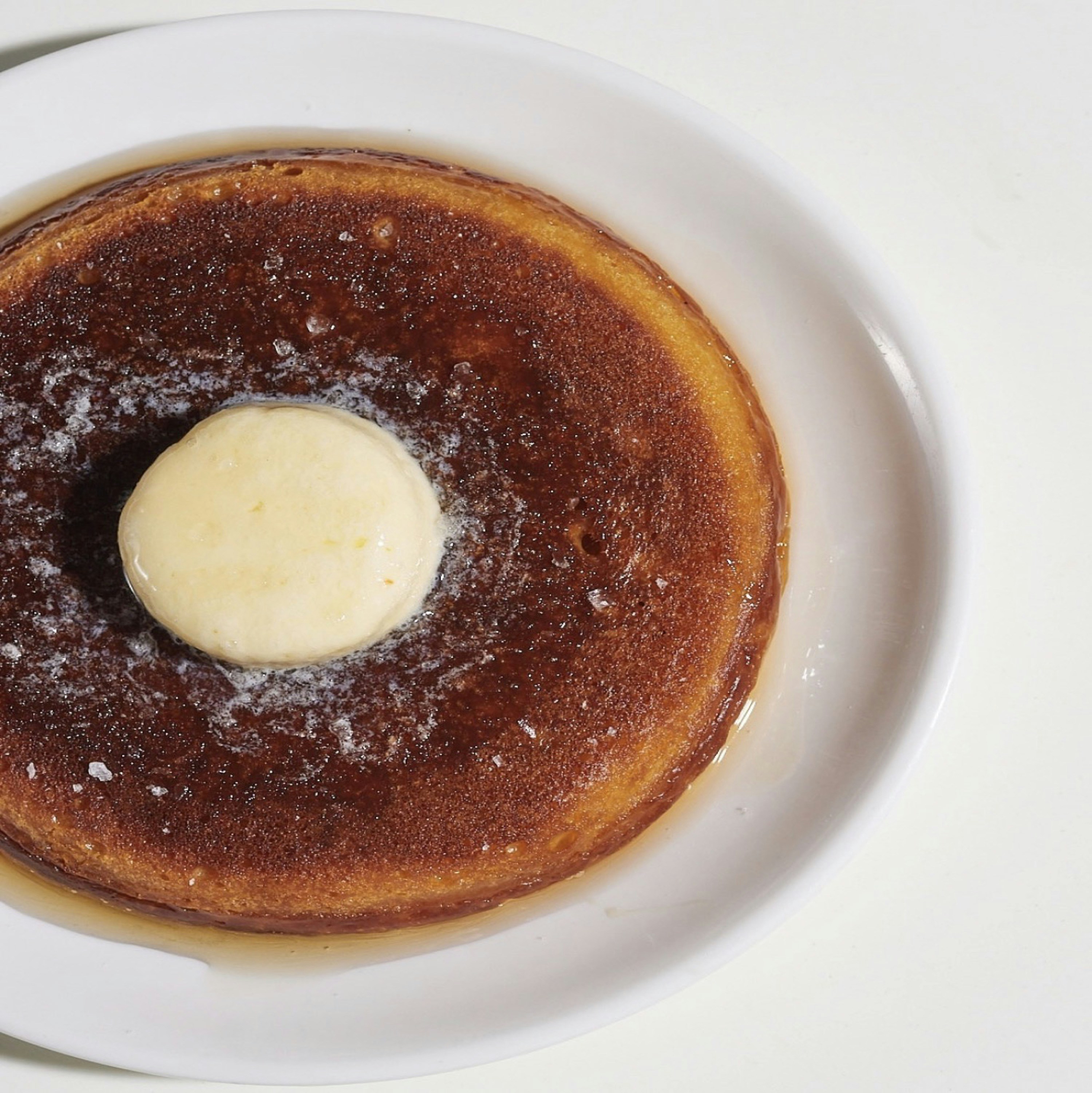 Pancake dorato guarnito con burro che si scioglie e sciroppo