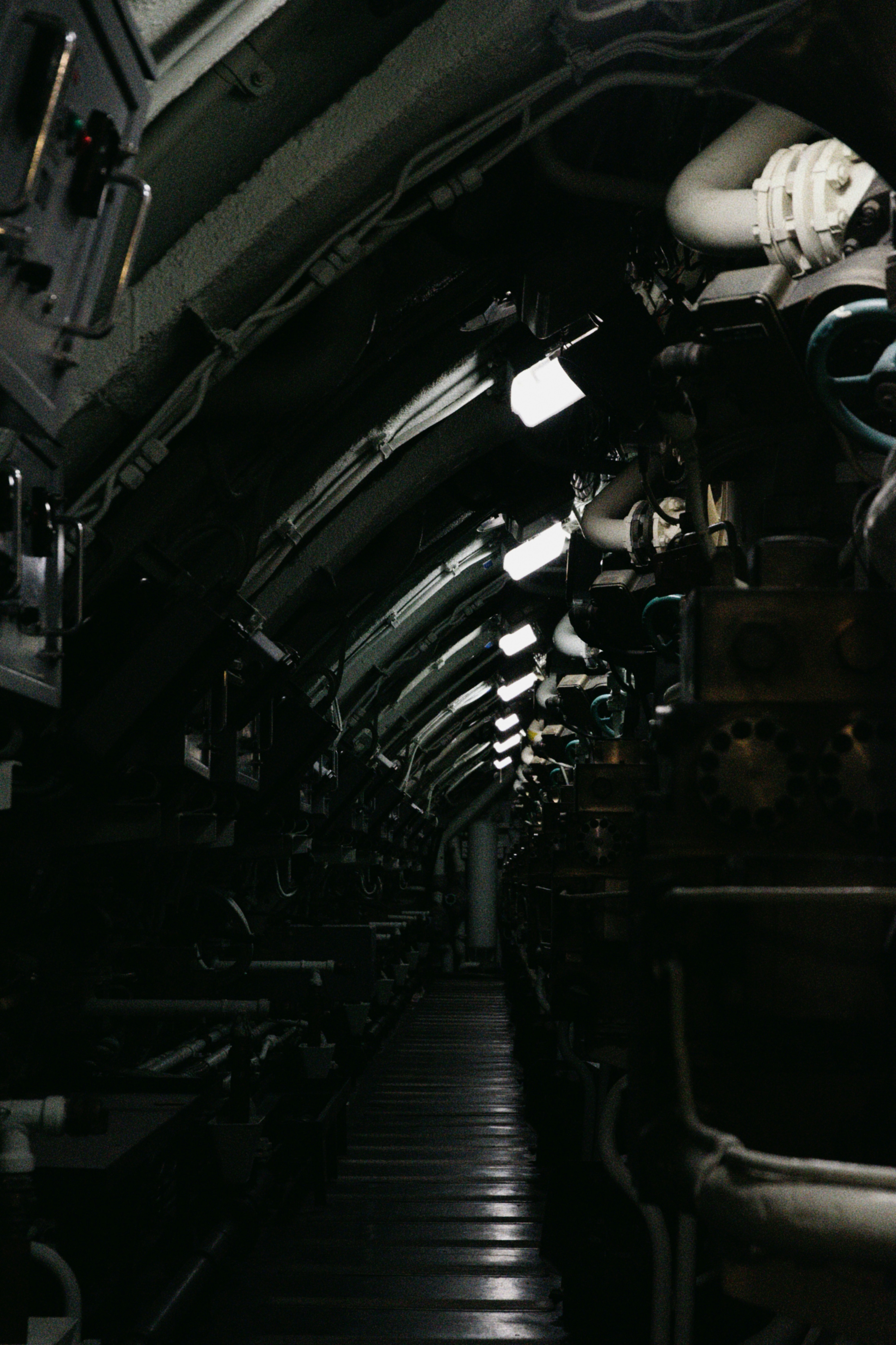 Dark, narrow interior of a submarine with overhead lights