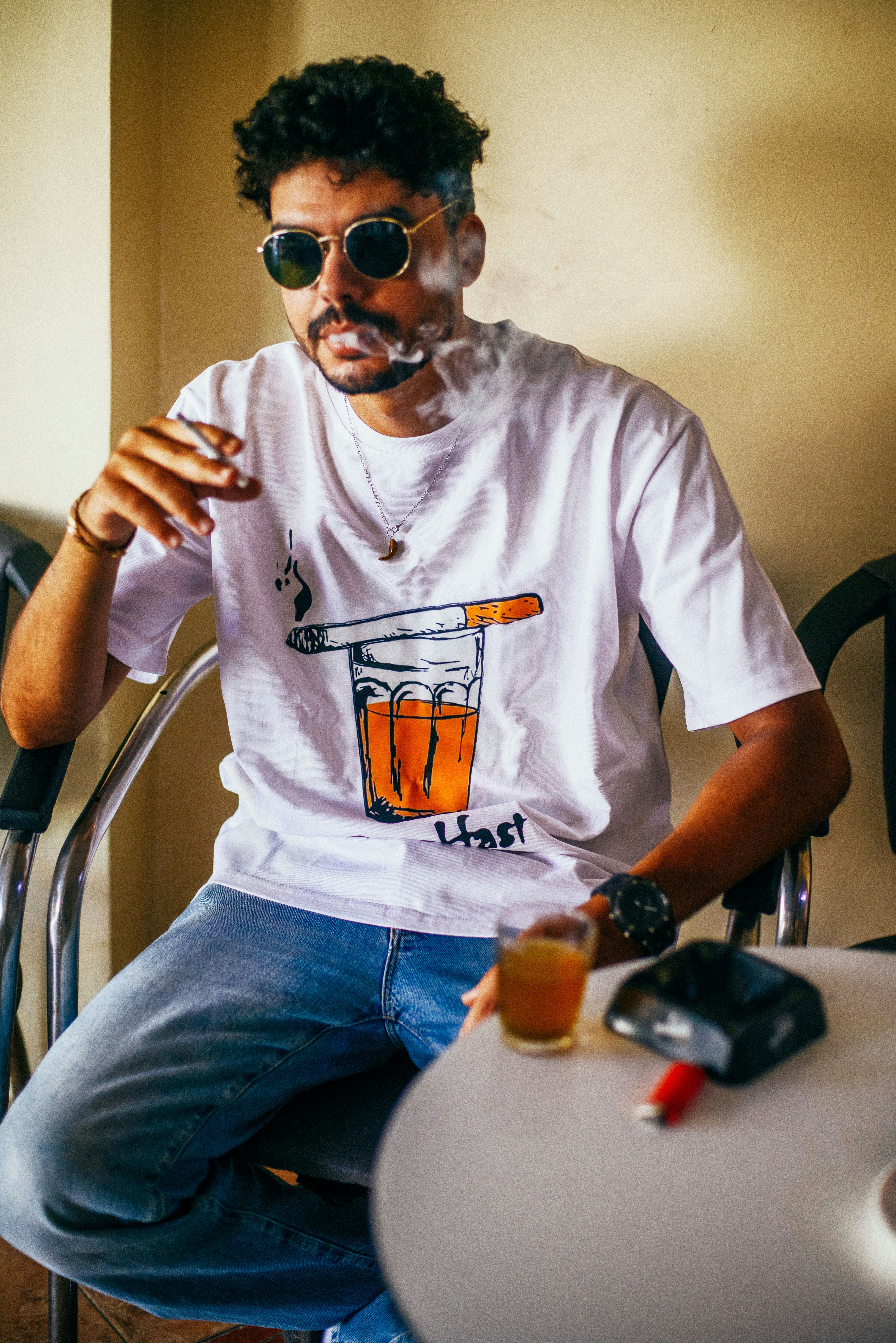 Man smoking cigarette wearing sunglasses and graphic tee