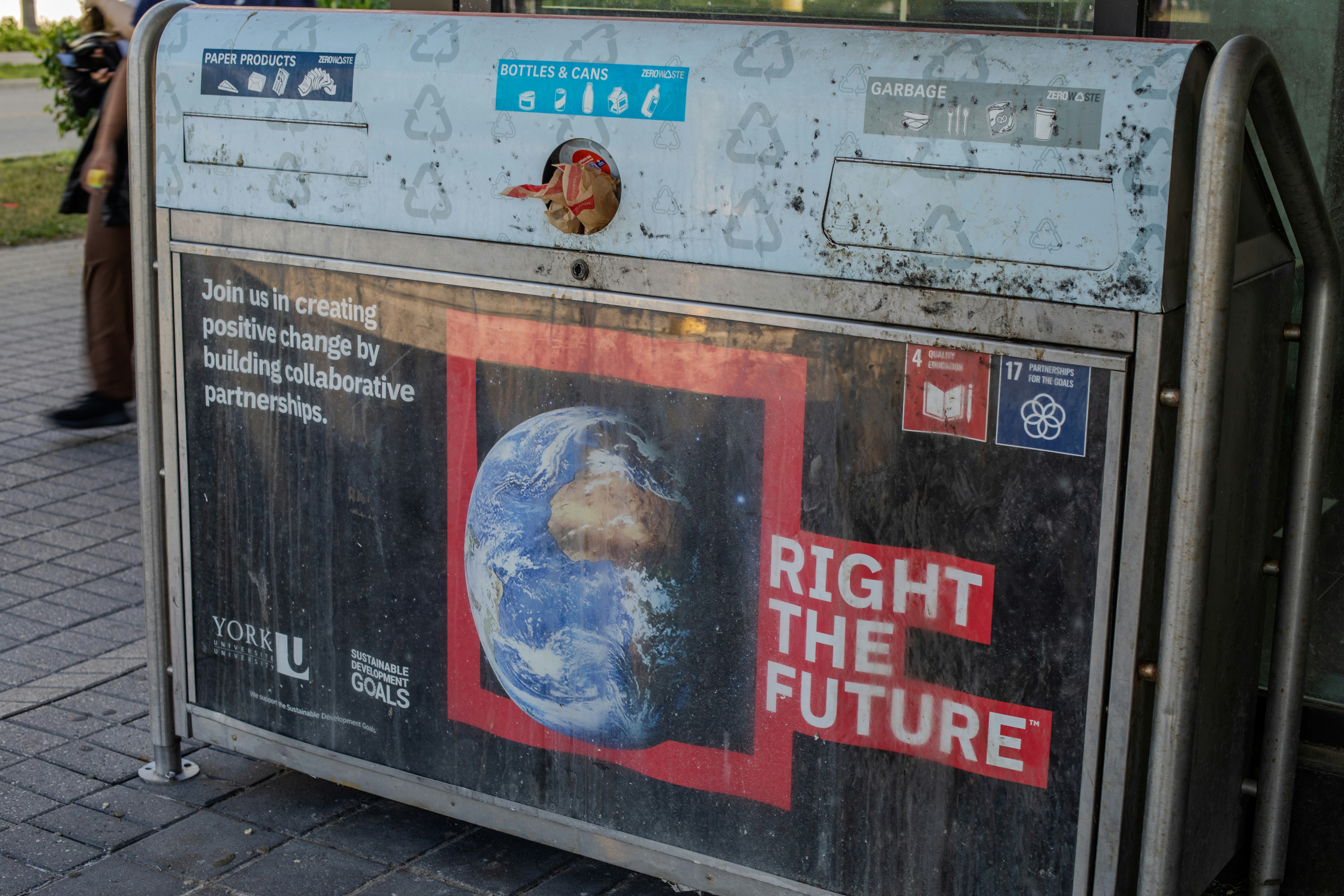 Dirty recycling bin featuring "right the future" slogan and earth