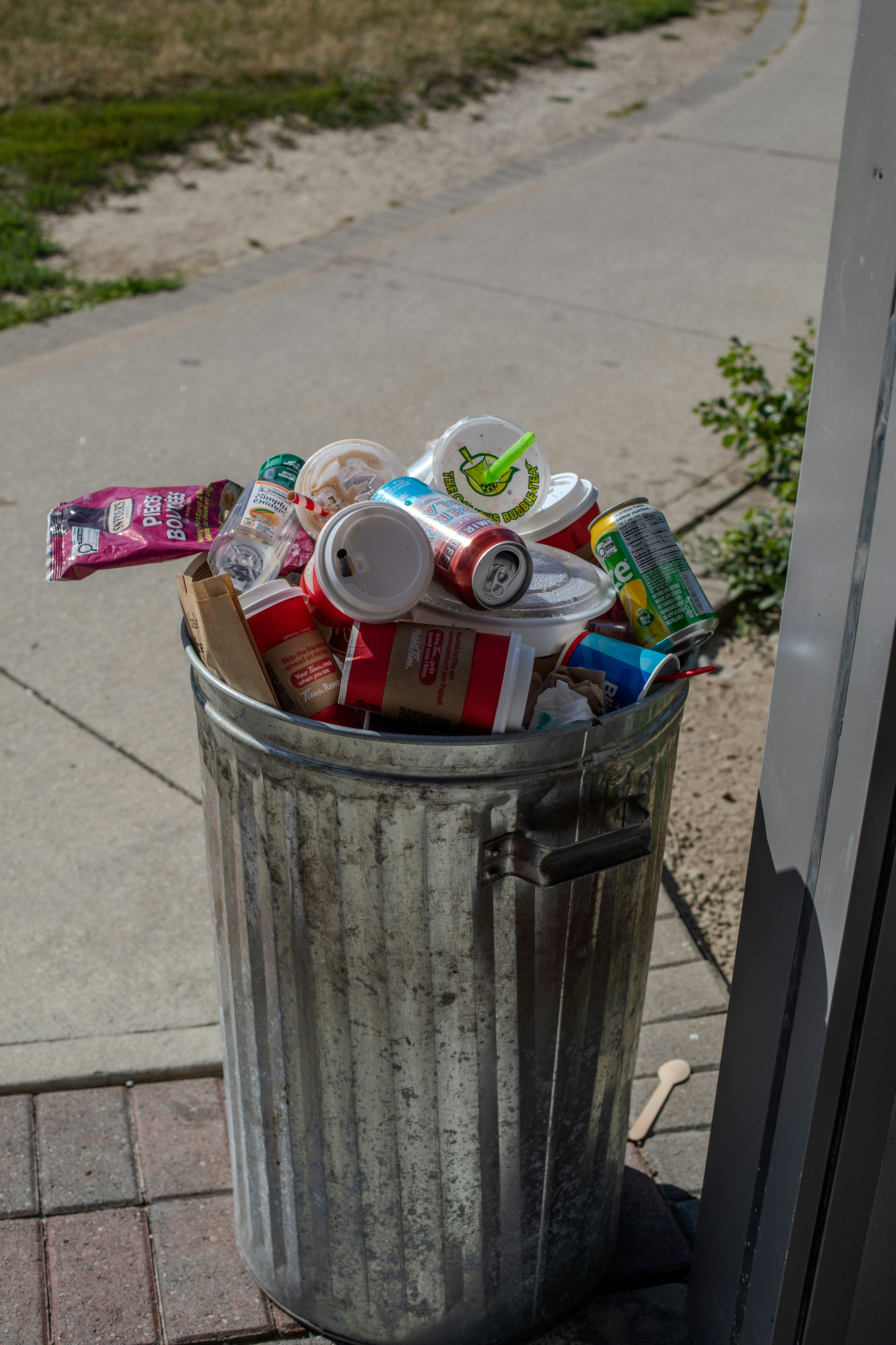 Overflowing metal trash can on a sidewalk